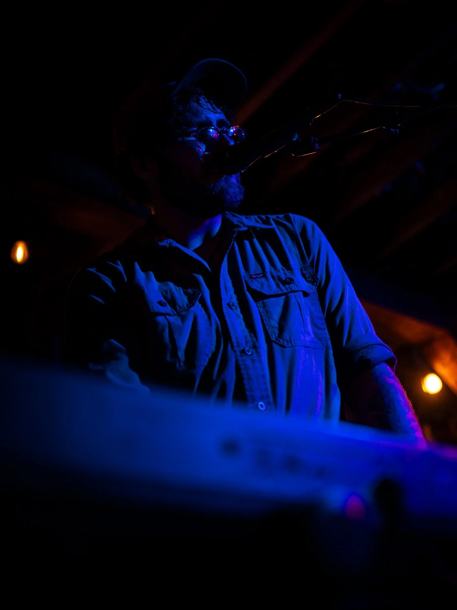 Local Fredericksburg artist Matthew James performing over piano keys. Night time photography, with blue, pink and yellow lights.