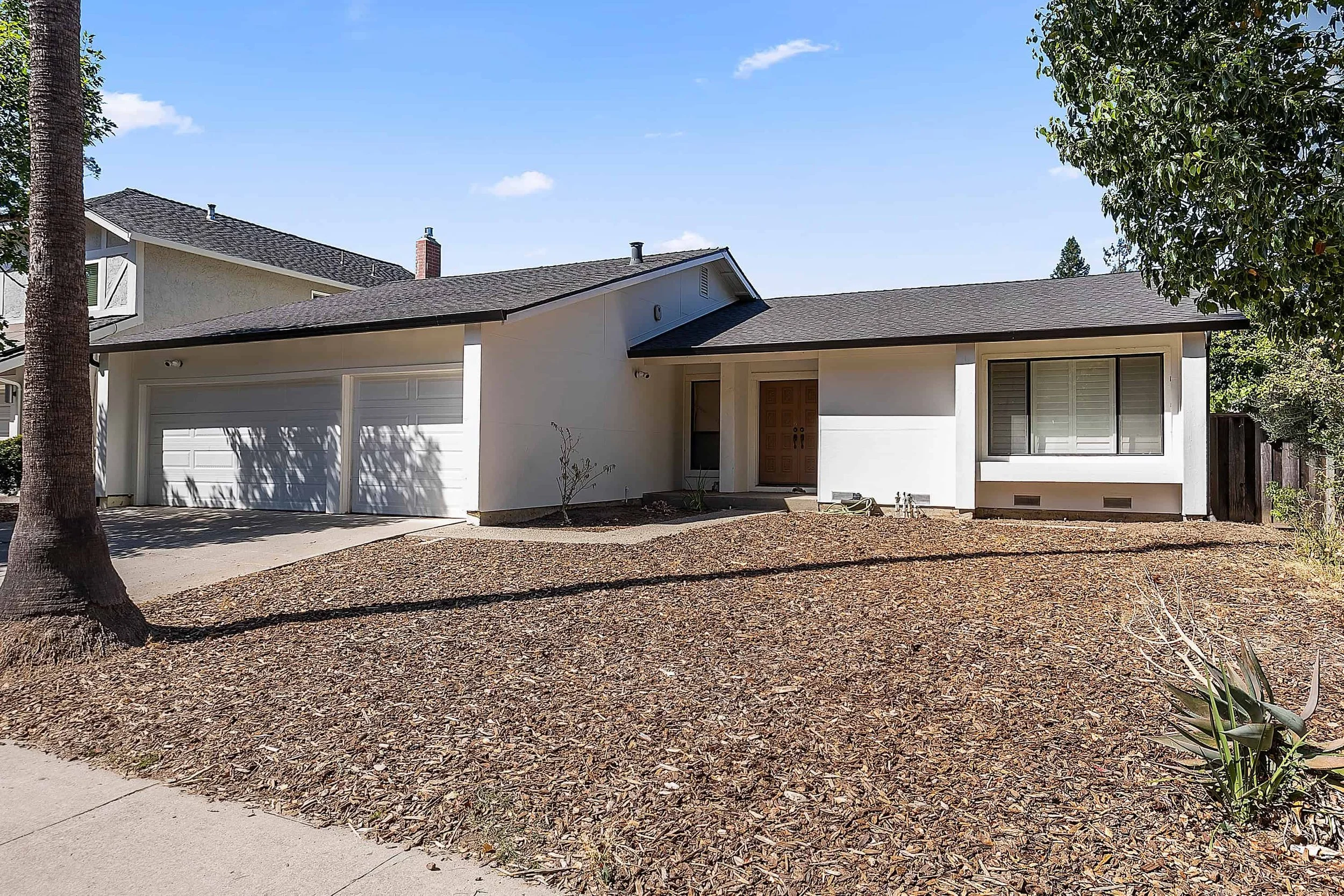 In San Jose a white bead and batten sided modern house with a large wood front door.