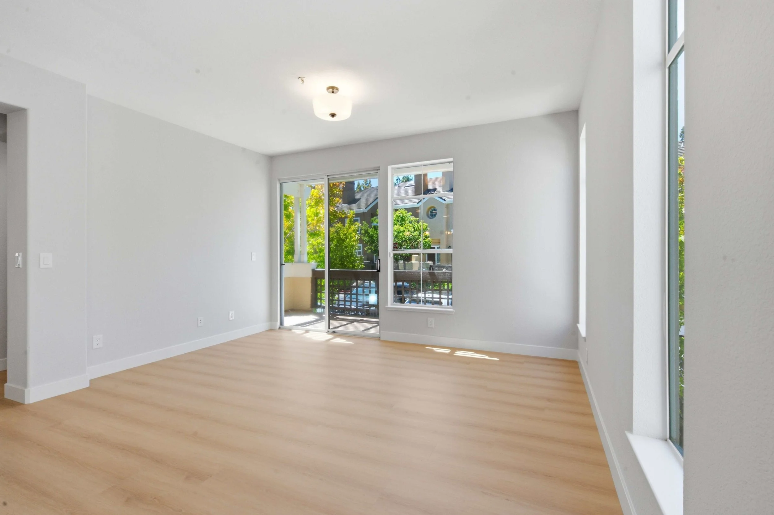 Dining area of a renovated condominium in Northern California. The room is unfurnished and focus on the new wood floors and new ceiling lighting.