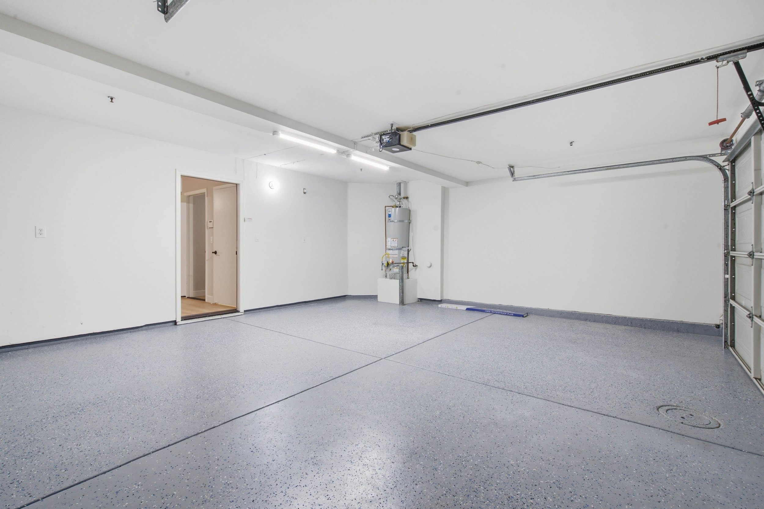 Renovated garage with resurfaced grey floors and white walls.