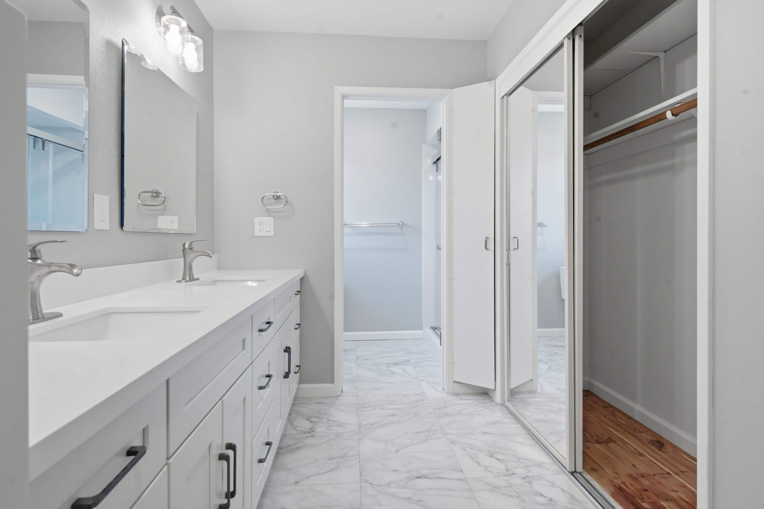 A renovated bathroom featuring a double vanity and built in closet.