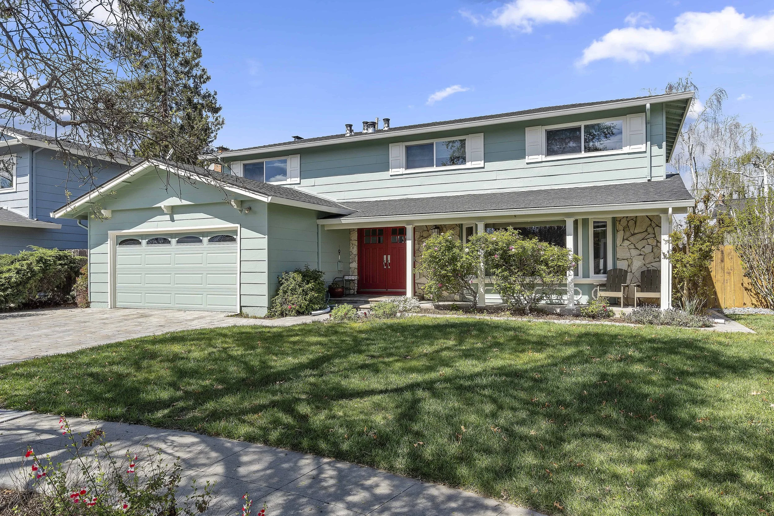 Two story sage house with new paint and siding. The house has red front door and white trim. 