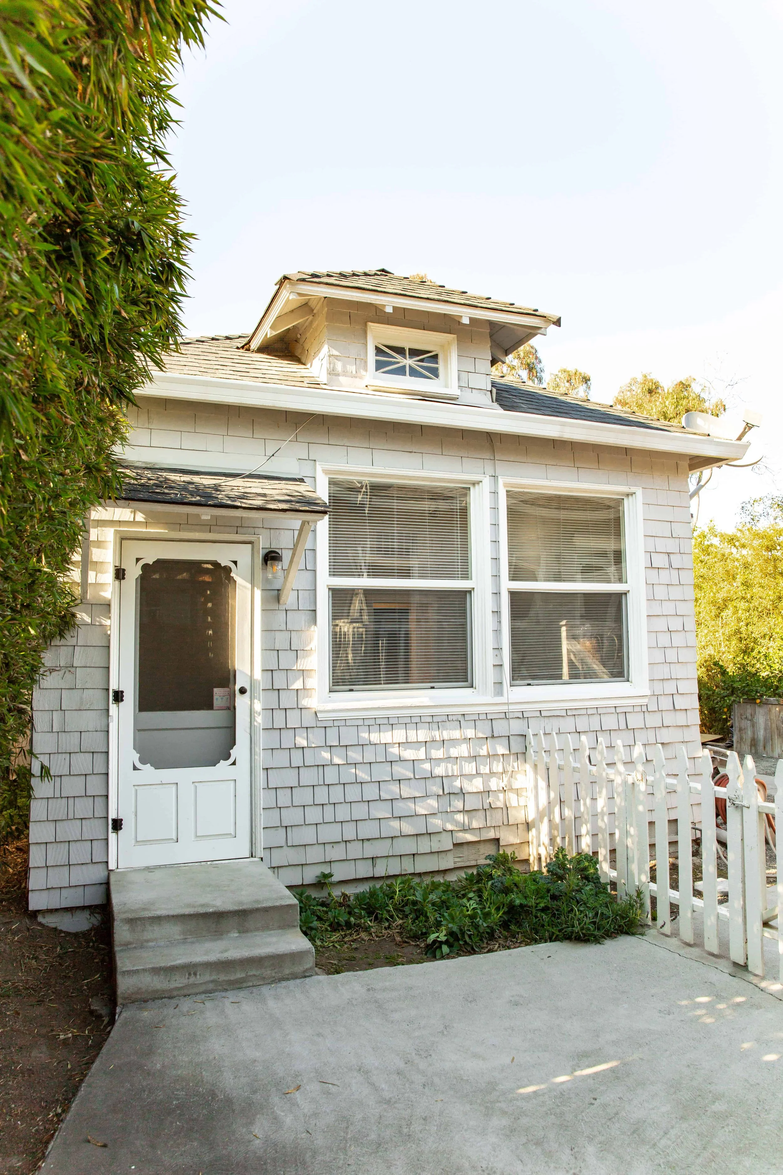 Entrance to a white ADU in San Jose, featuring a small patio. The shingles are painted rustic white.