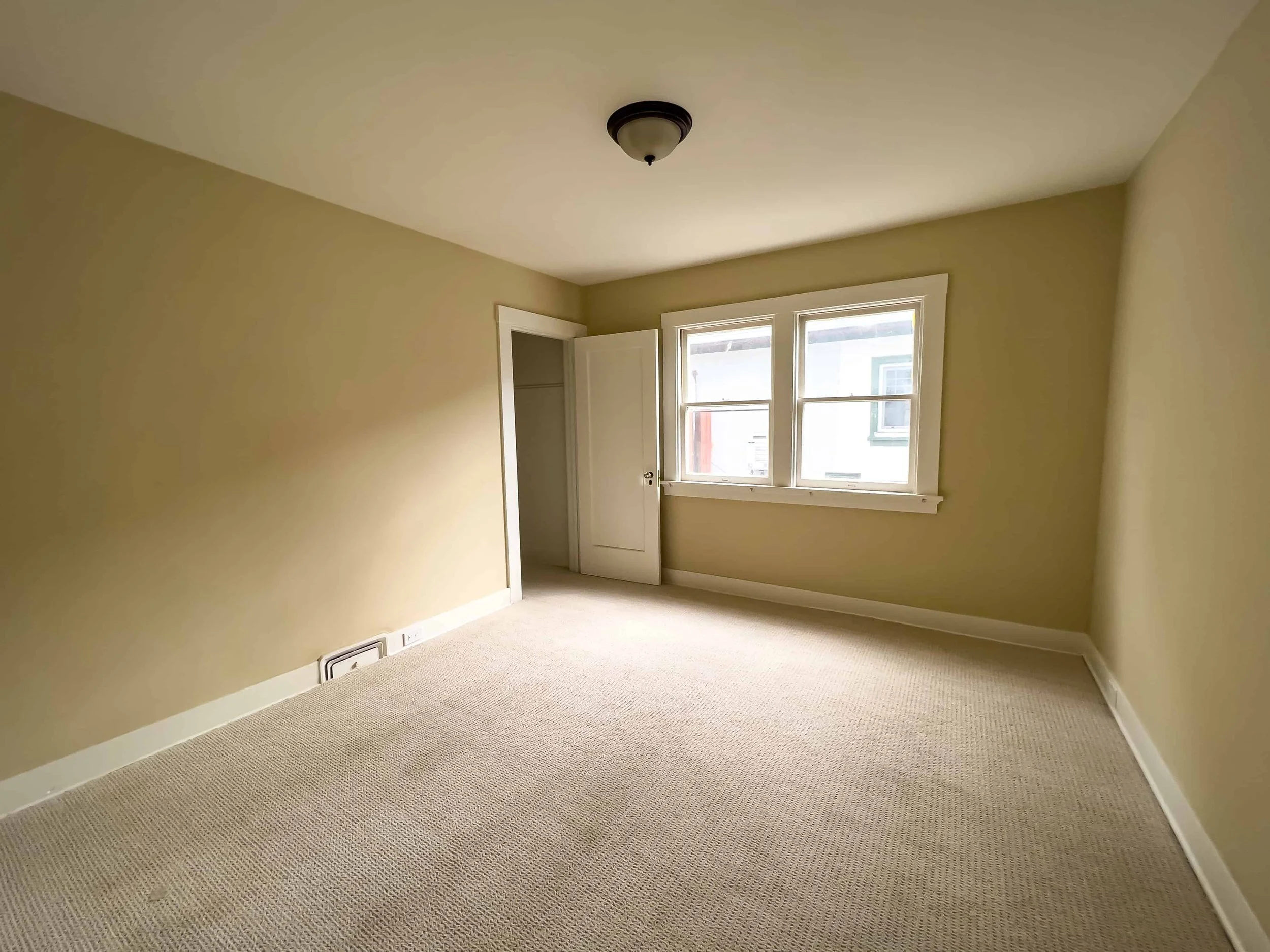 Refurbished bedroom with new carpet and beige walls. The room is empty.