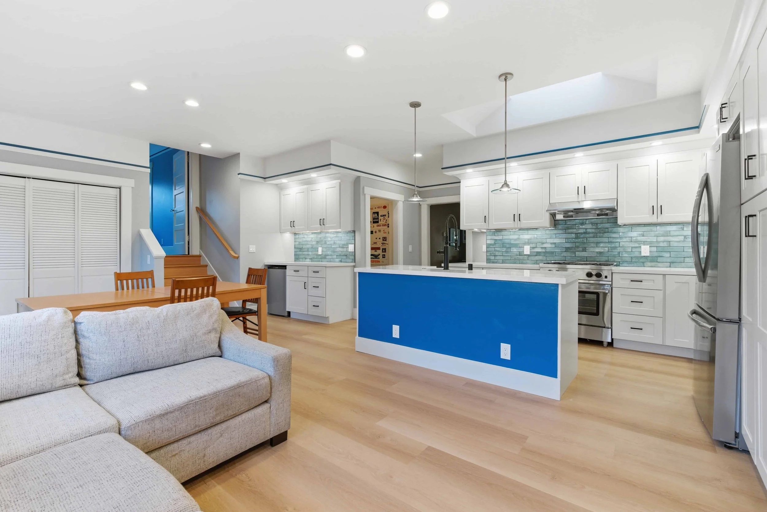 Remodeled kitchen from the media room. The blue kitchen island is the focal point with the working kitchen in the background.