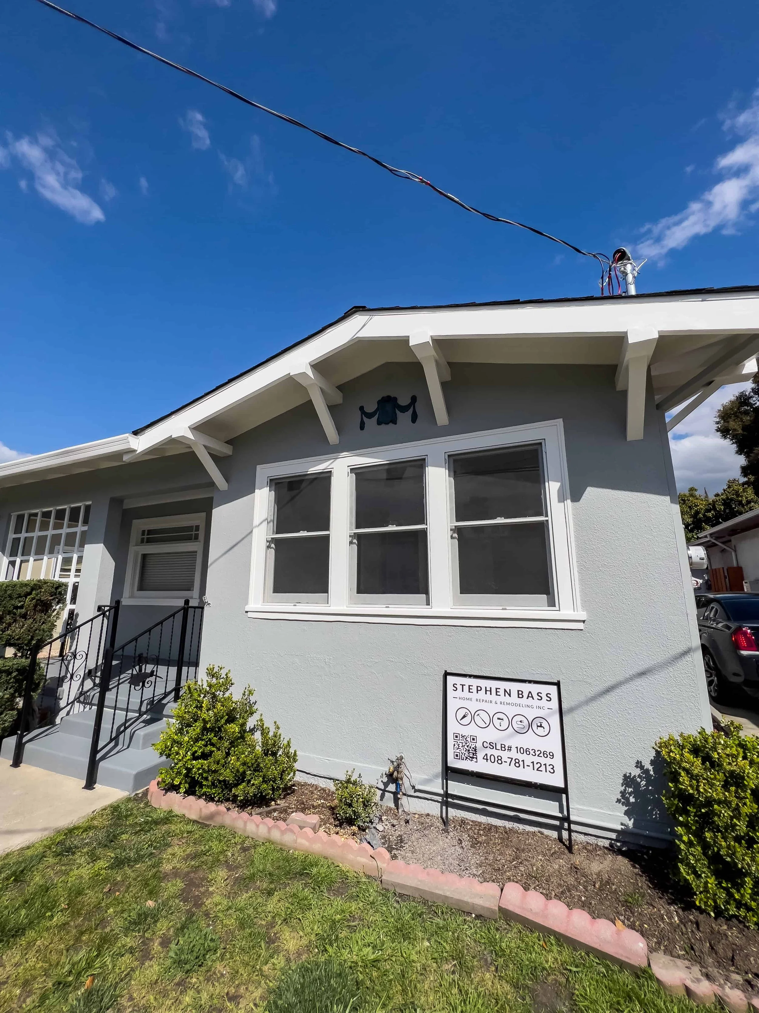 Front section of a craftsman home painted gray with white trim around the three windows.
