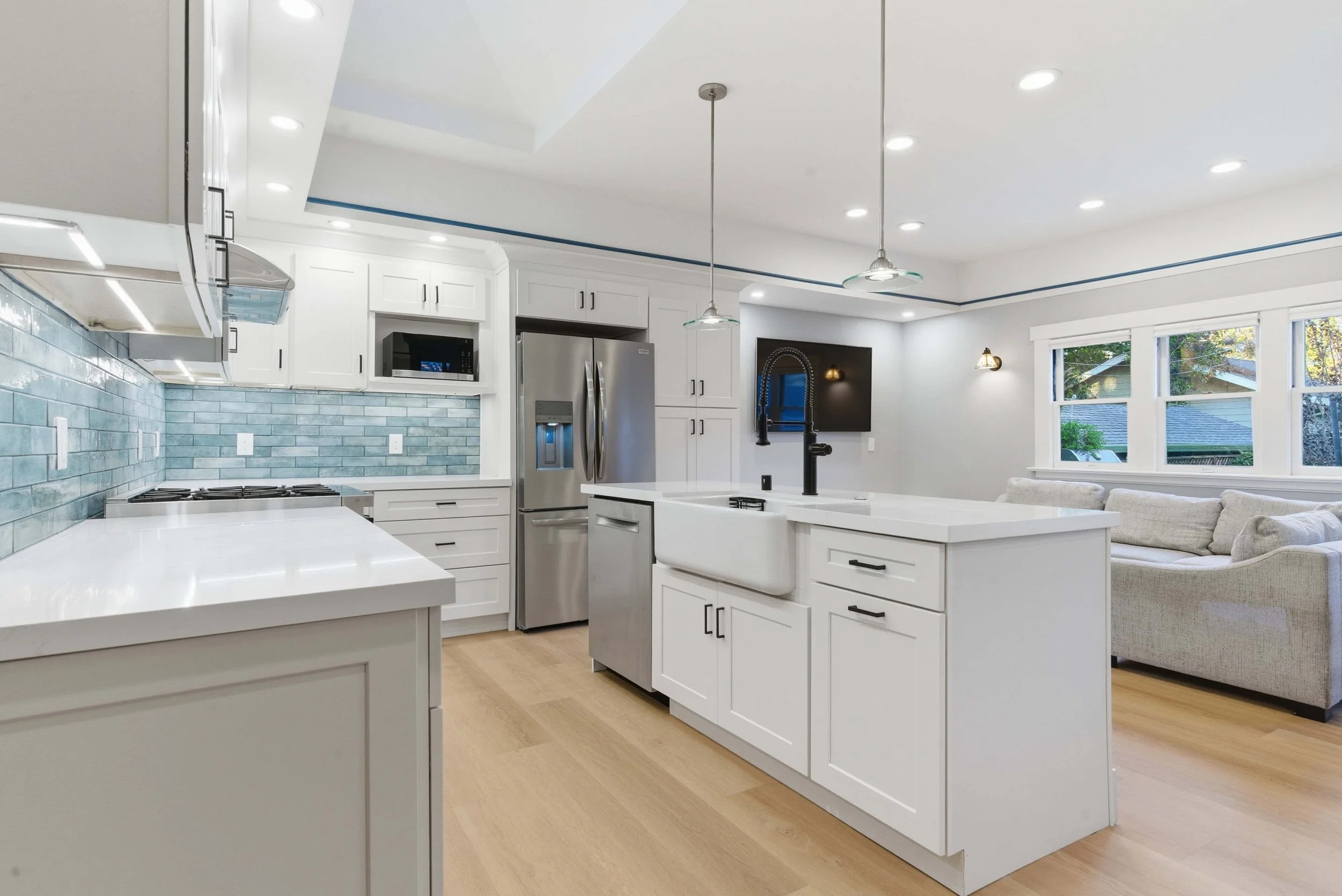 Kitchen with wood floors, marble countertops, stainless appliances, and white cabinets.