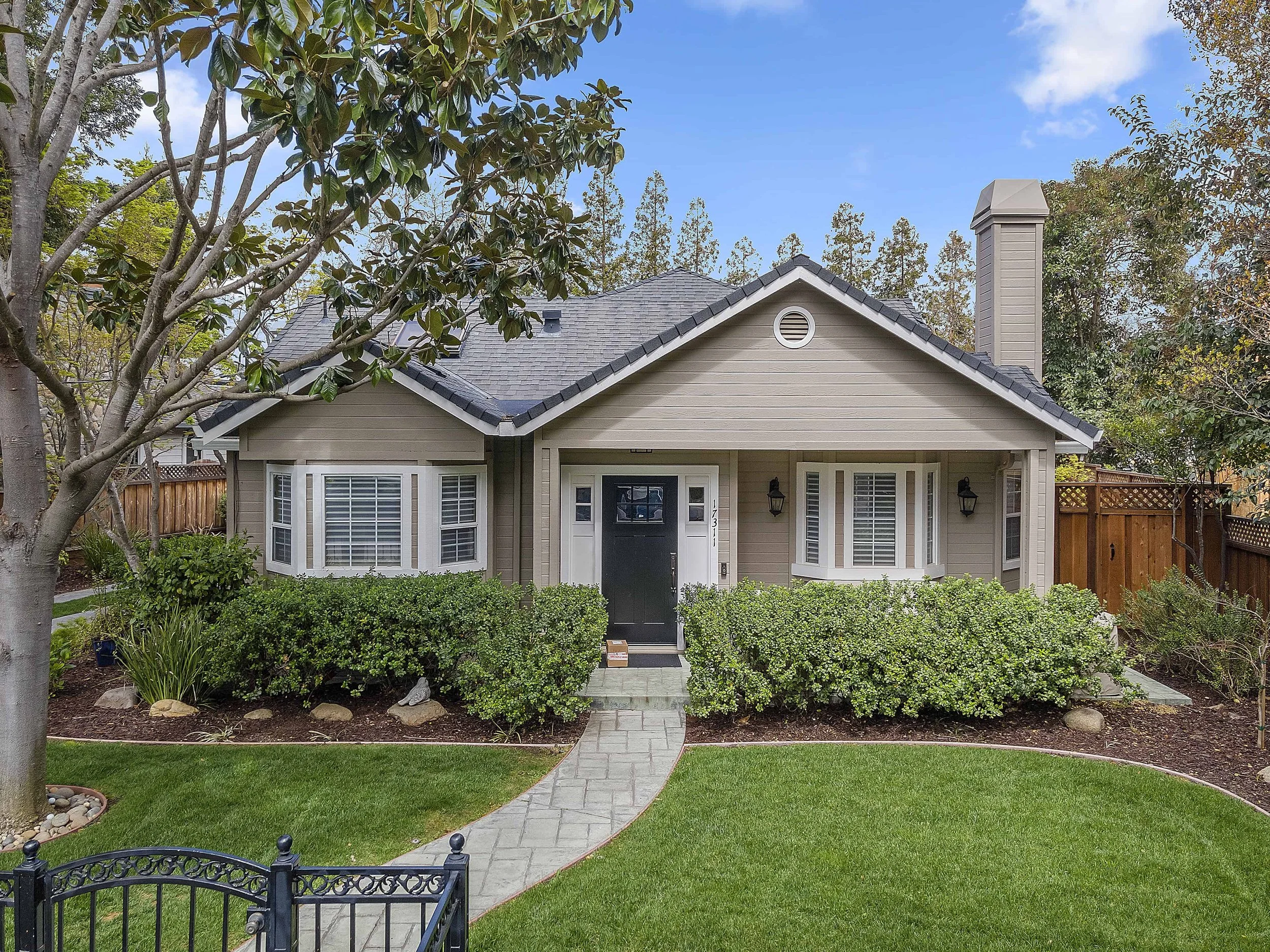 Street view of a newly painted historic home in San Jose in beige with white trim and a black front door.