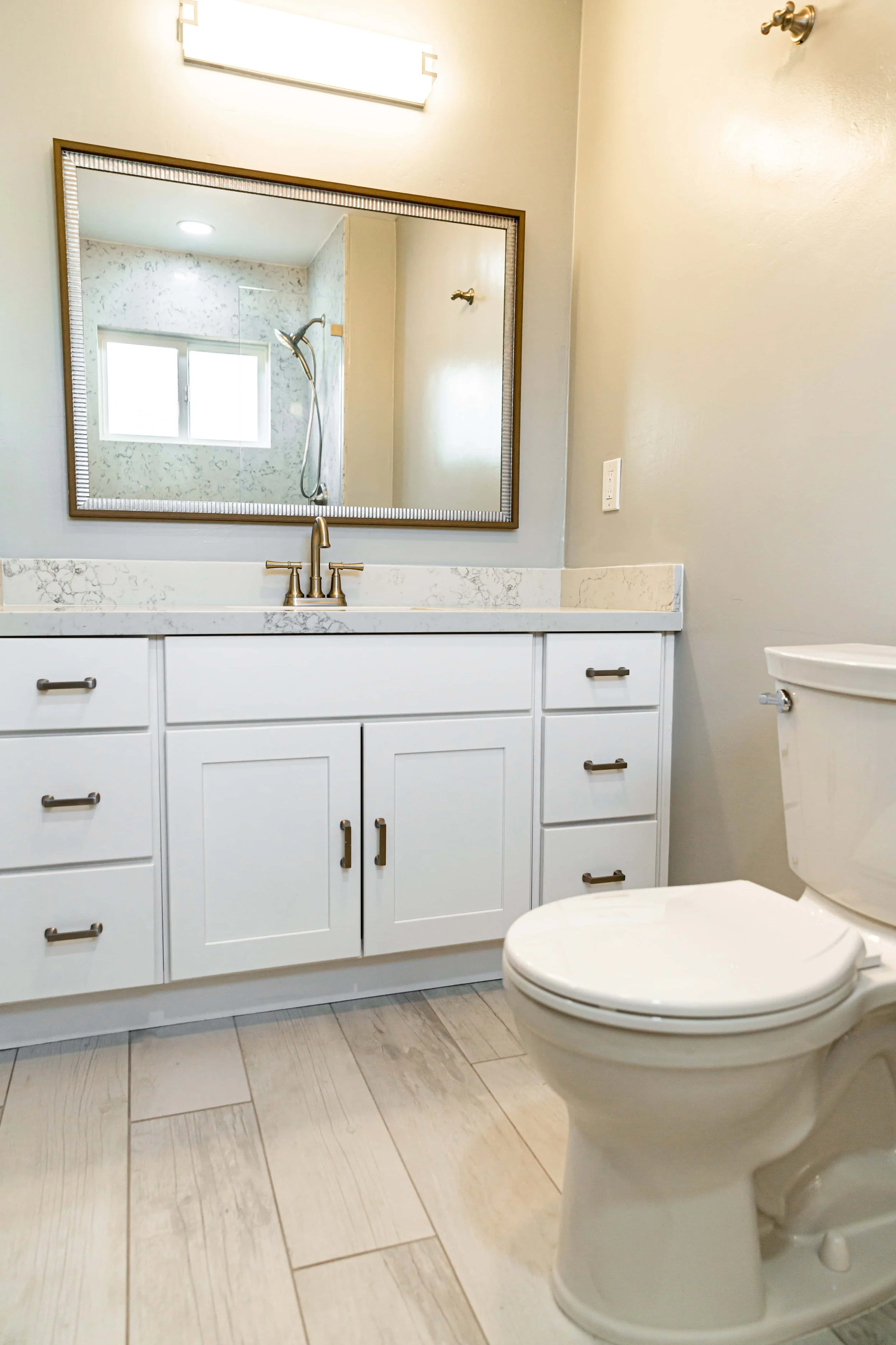 A renovated California bathroom with bright, light walls, marble, and bright white plank flooring