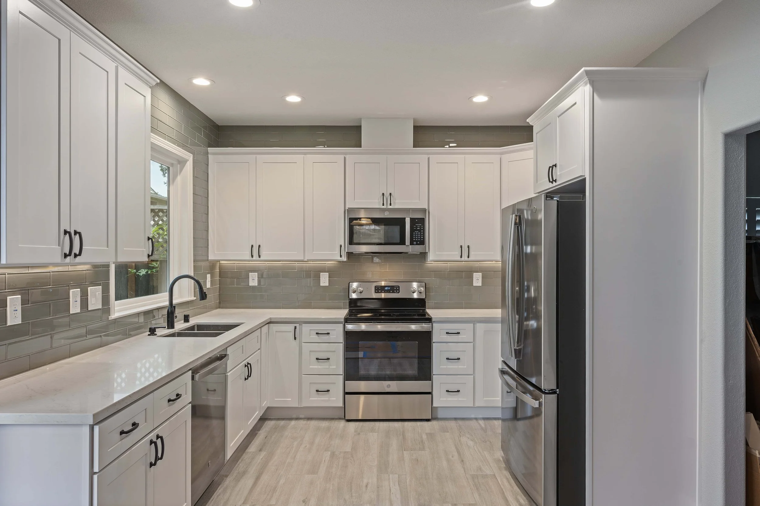 A galley style kitchen in San Jose, remodeled in bright white and grey. They cabinets are white, and the countertops are natural white. 
