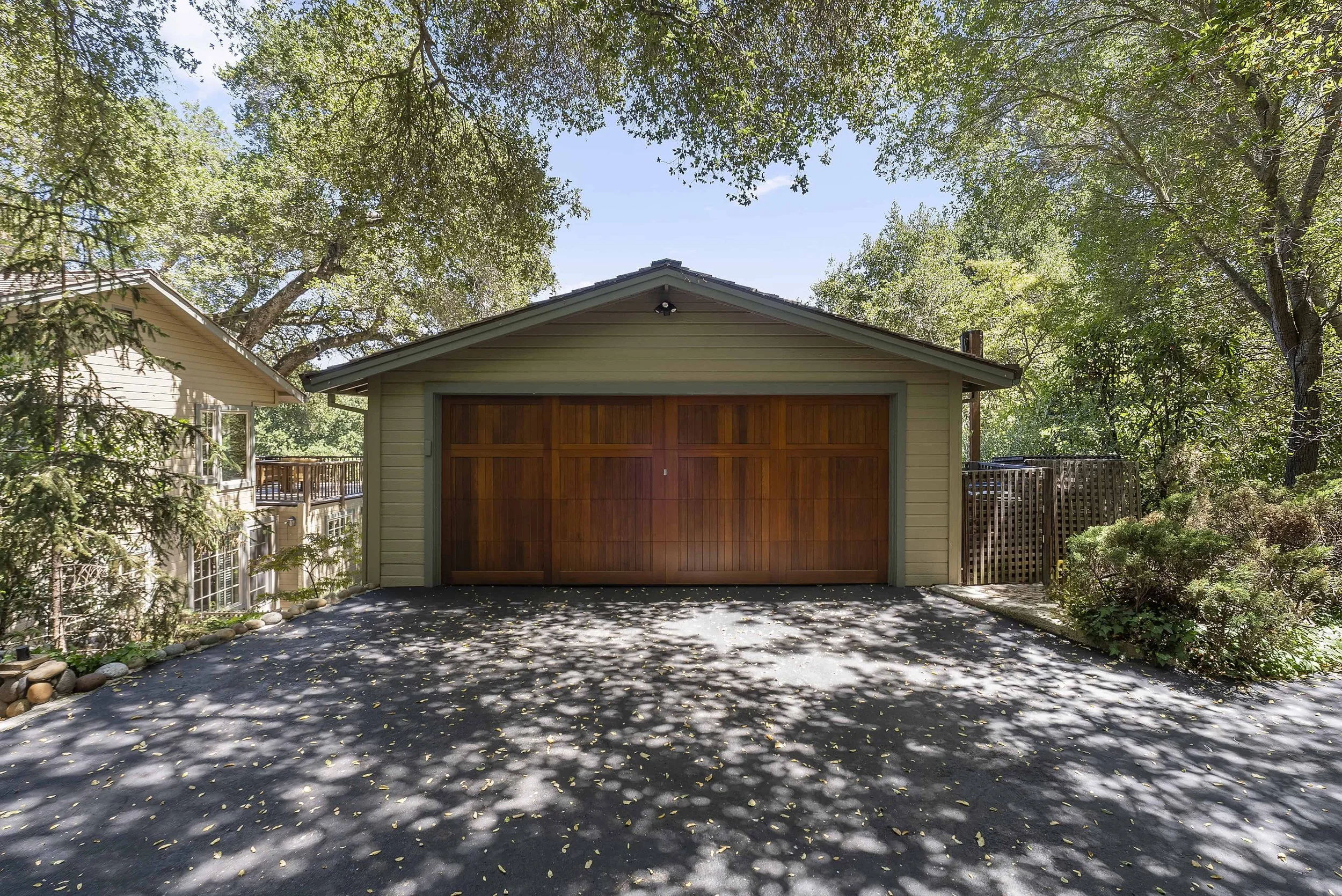 Refurbished craftsman garage with new green horizontal siding and a wood stained door.