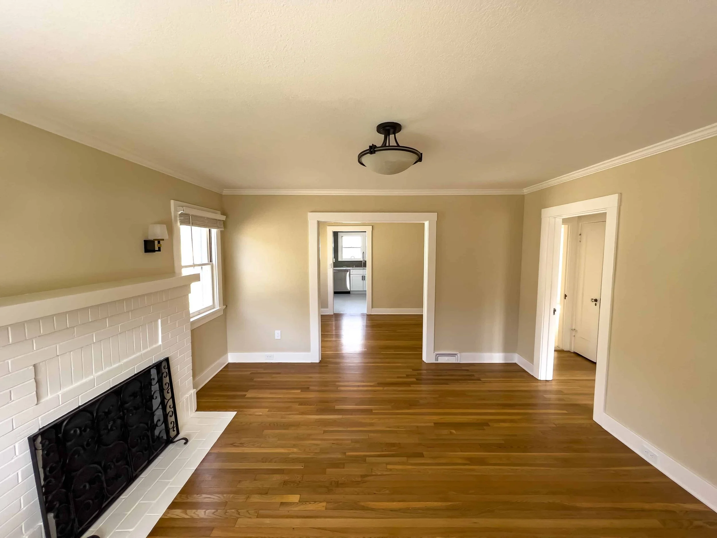 Interior of a craftsman cottage in San Jose, the hardwood floors are refinished, the fireplace painted white and restored, and the walls are painted beige.