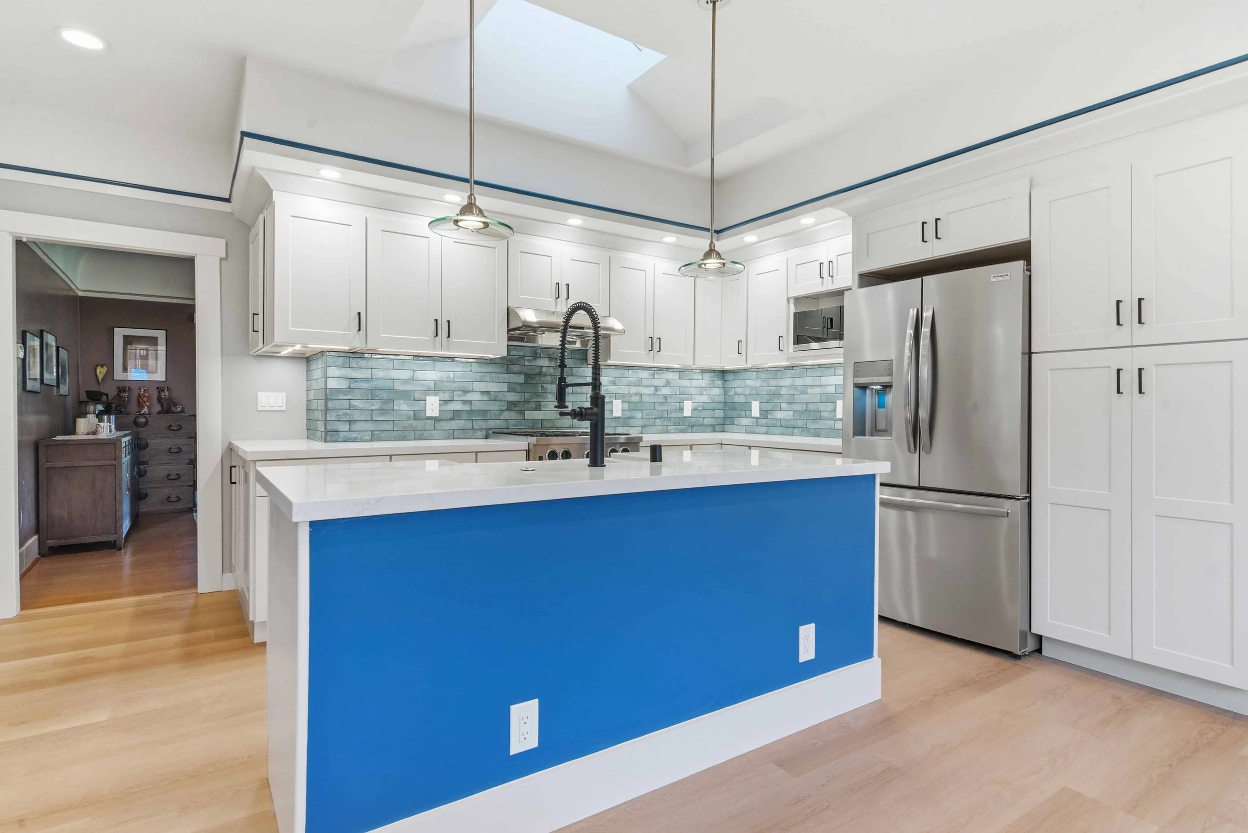 Bright blue kitchen island with pendant lamps lighting the work area.