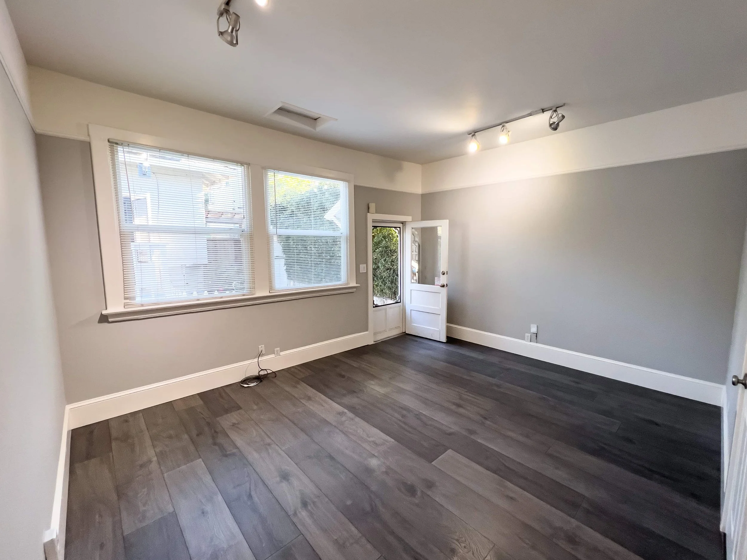 Dark flooring in an ADU. The walls are warm grey with soft lighting. Windows are in the background letting in natural light.