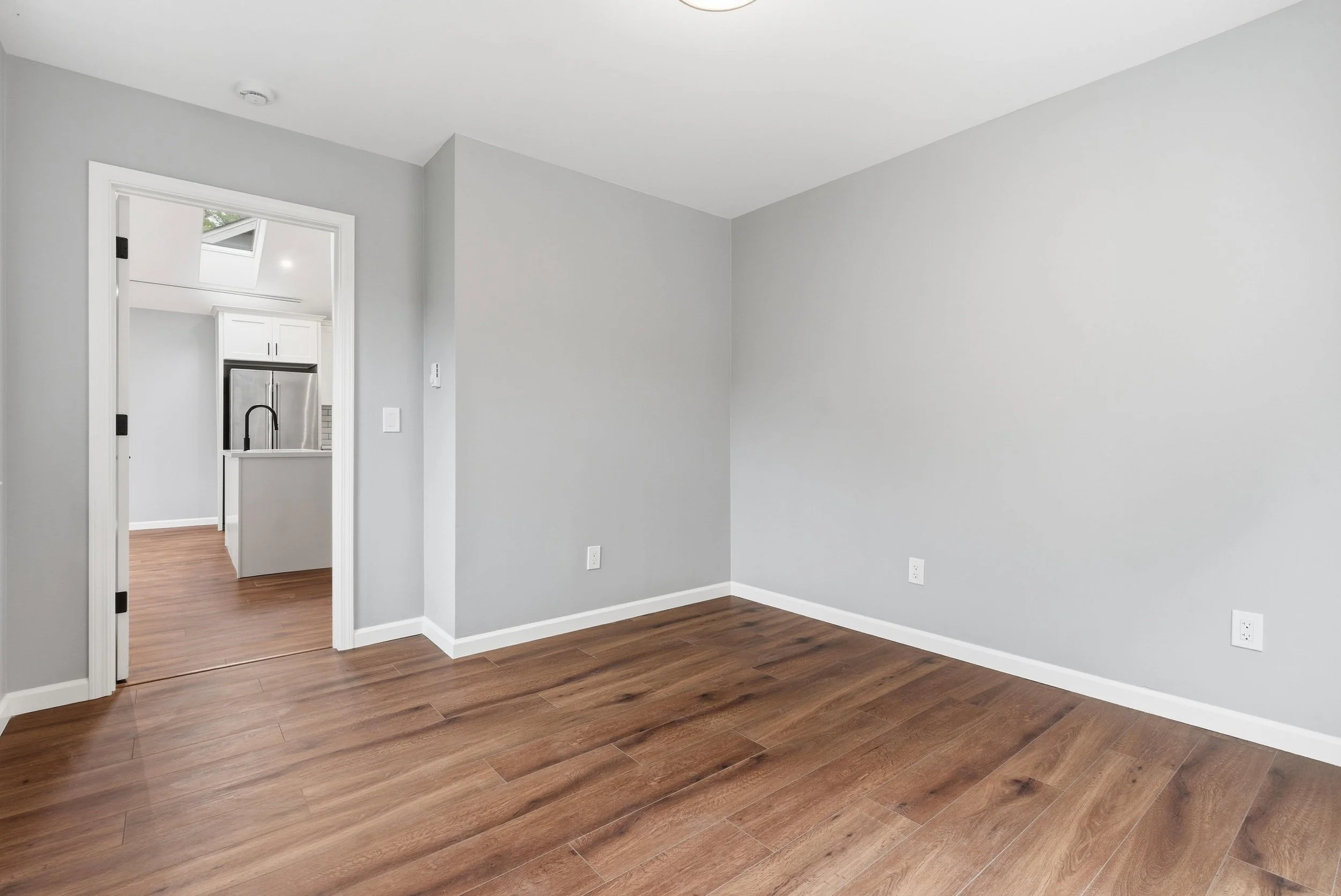 ADU interior with hardwood floors and gray walls. The room is empty.