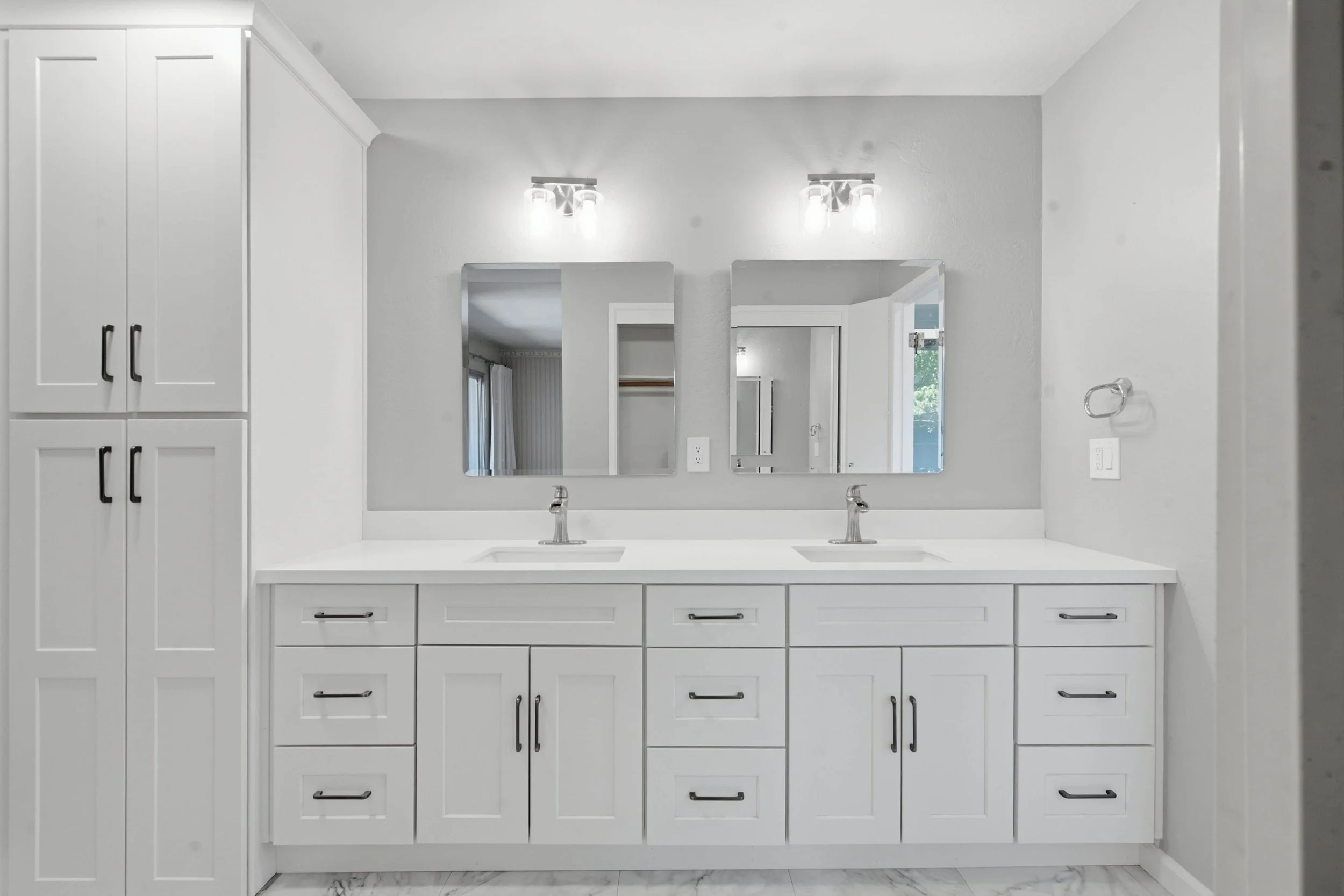 A bright white bathroom vanity with double sinks and white cabinetry for storage.