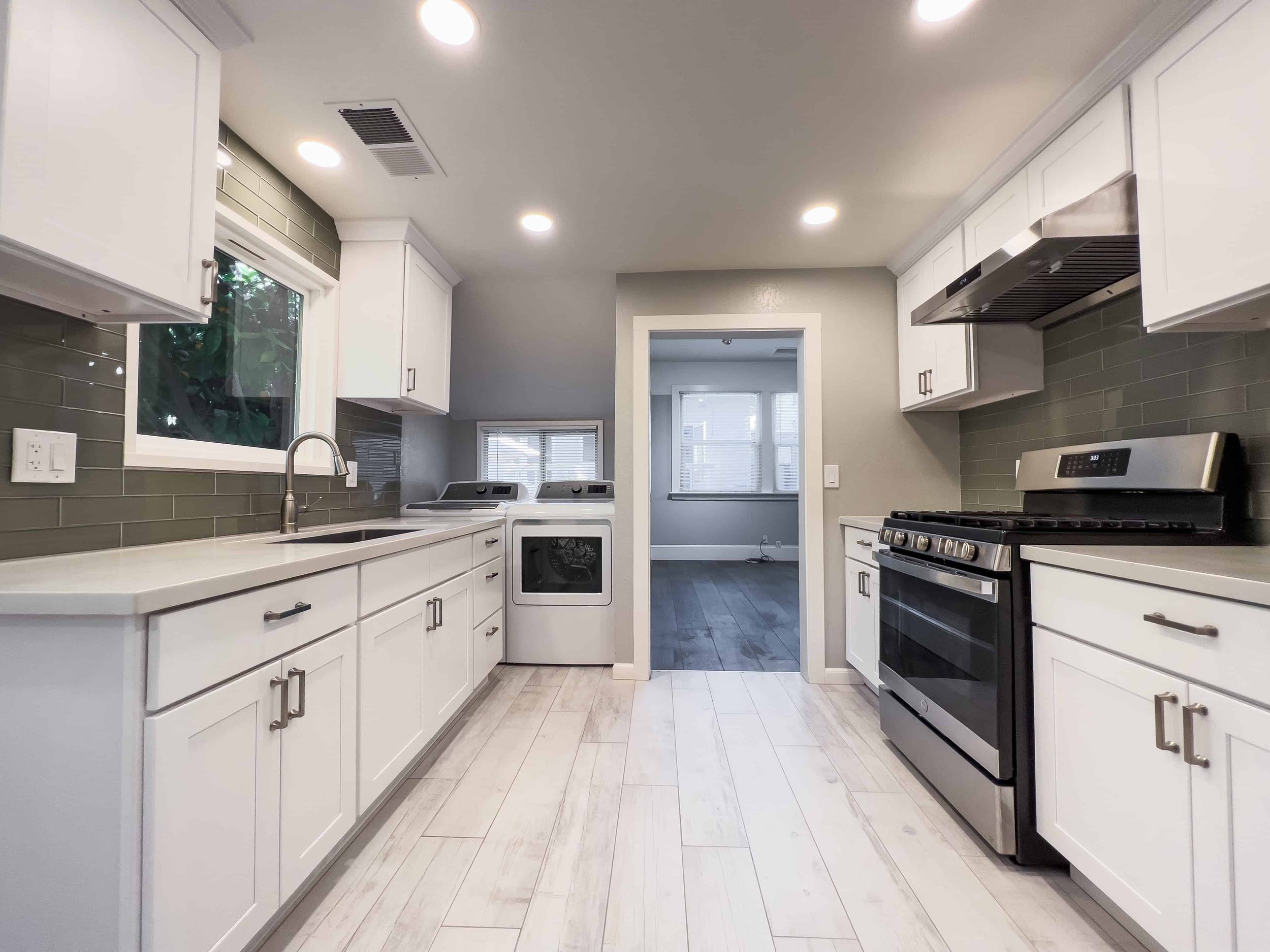 Kitchen in a downtown San Jose ADU, featuring white plank flooring and white cabinets.
