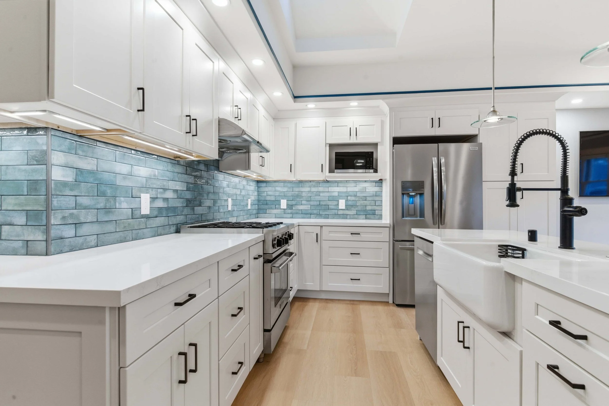 New kitchen with blue glass tile backsplash and white cabinets. 