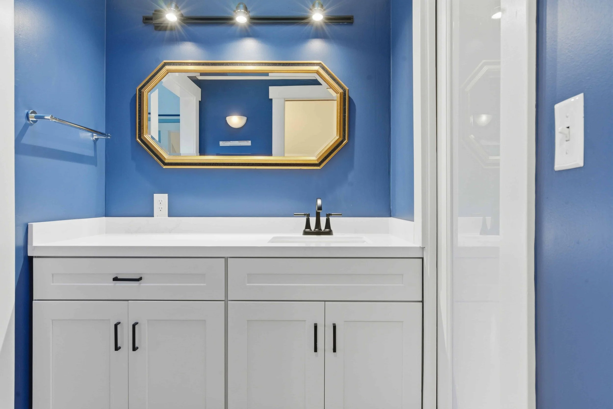Blue walls and white vanity in a remodeled half bath.