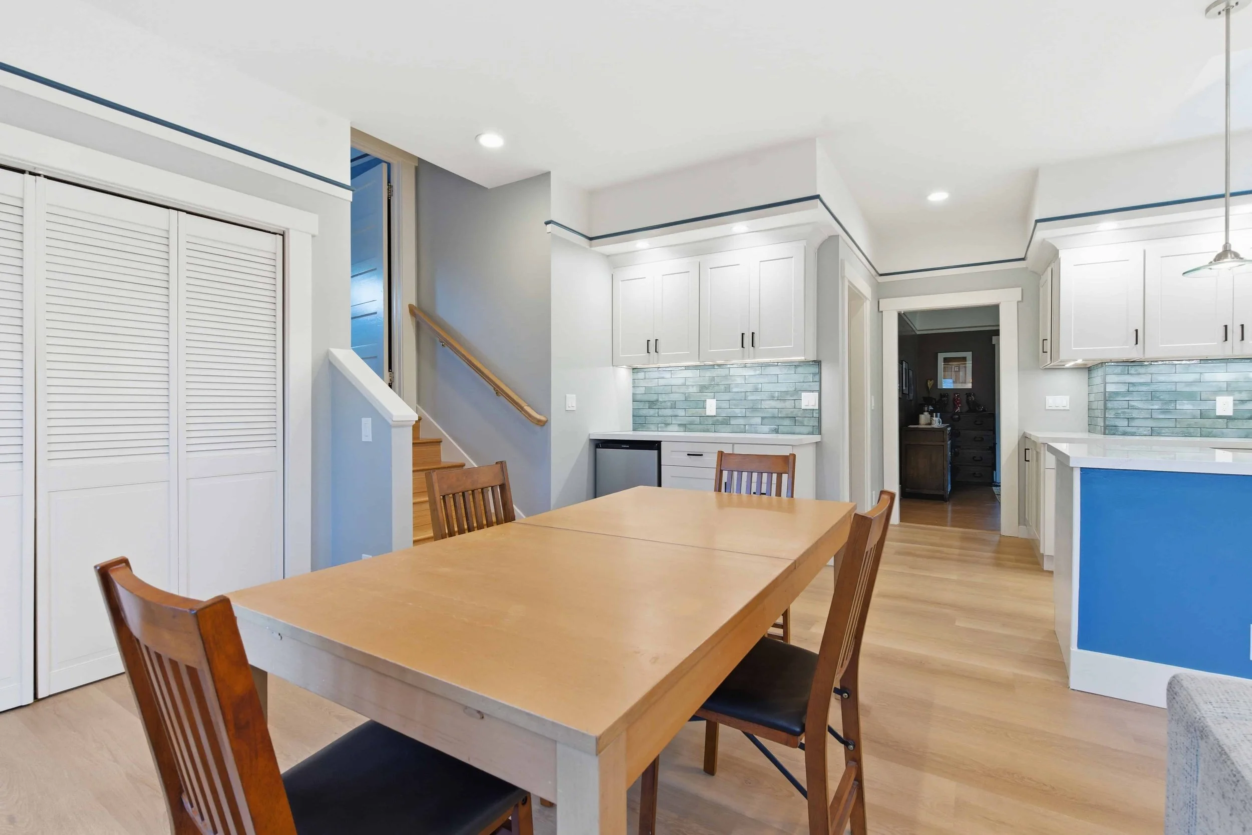 Naglee Park San Jose remodeled kitchen with a dining area that has a large wood table and chairs. The working kitchen is in the background including a bright blue kitchen island.