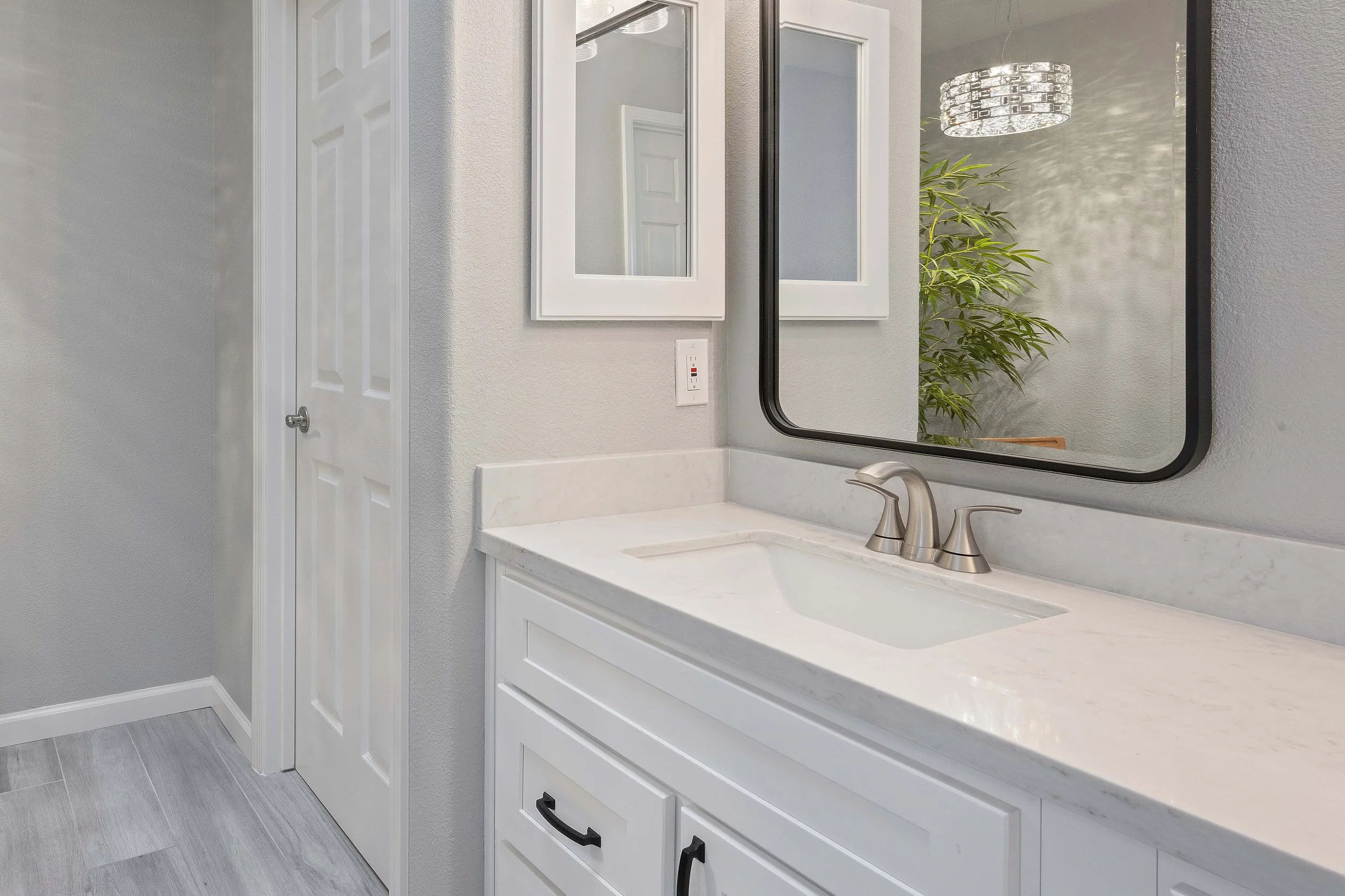 Mirror in a master bathroom hanging over one half of a white double vanity.
