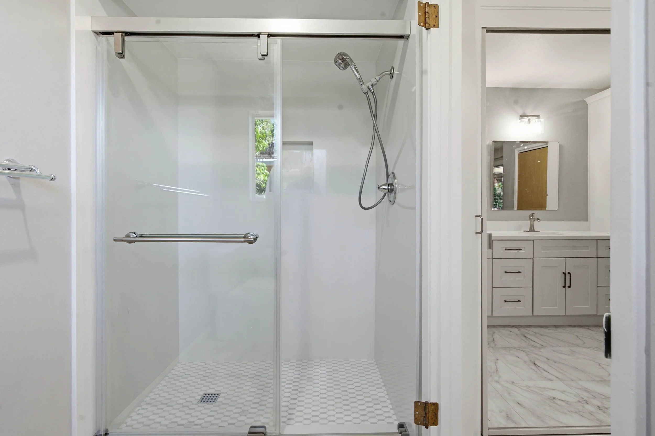 A walk in shower with white tiles.
