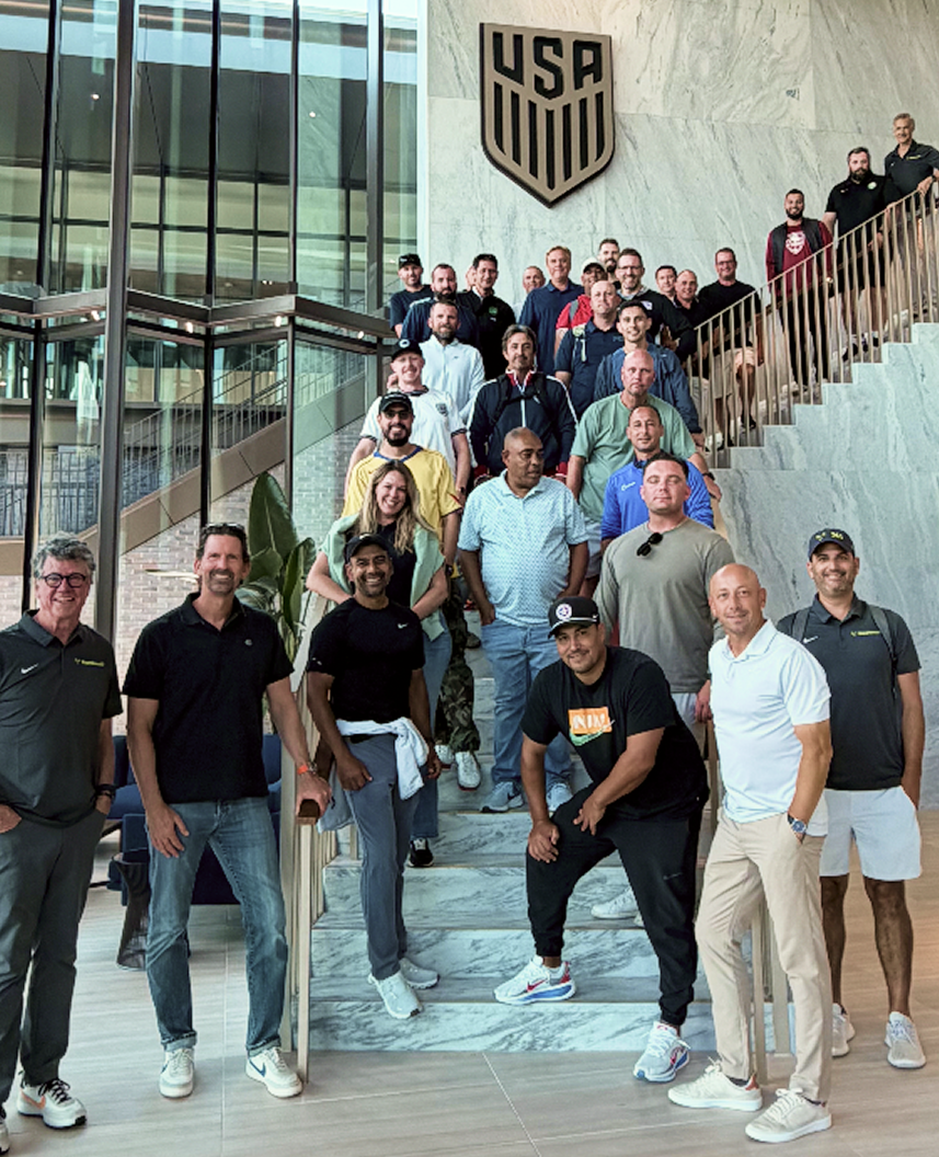 Group of people standing on stairs inside a modern building with a large USA UNID logo on the wall.