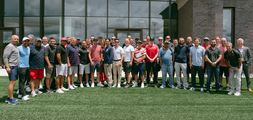 Group of men standing on grass outside a modern glass building