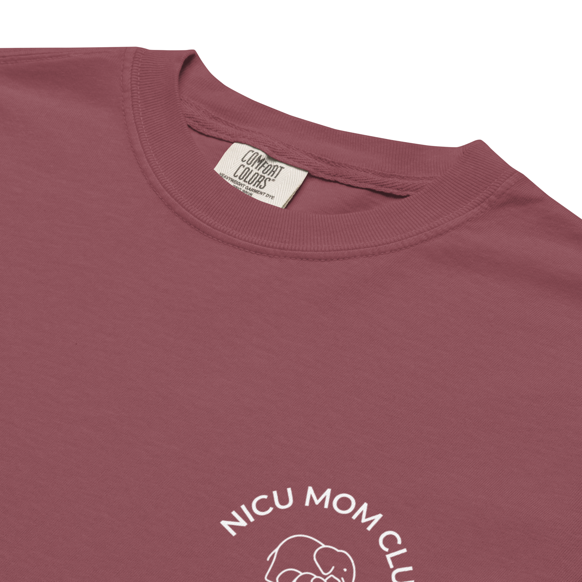Close-up of the small white NICU Mom Club chest design on a berry Comfort Colors T-shirt.
