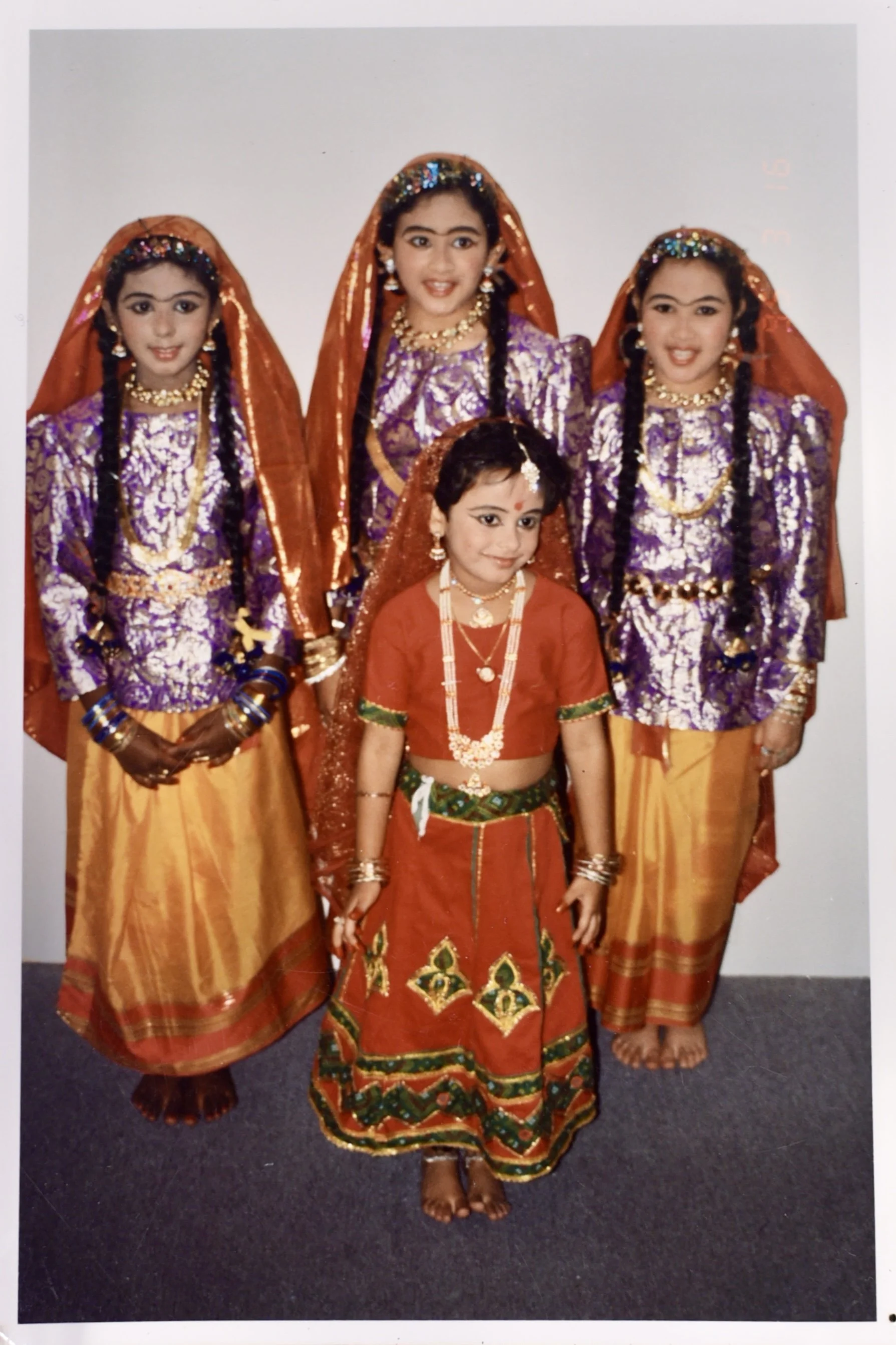 Samantha Juan with a group of young women wearing colorful traditional clothing during her childhood in Bahrain.
