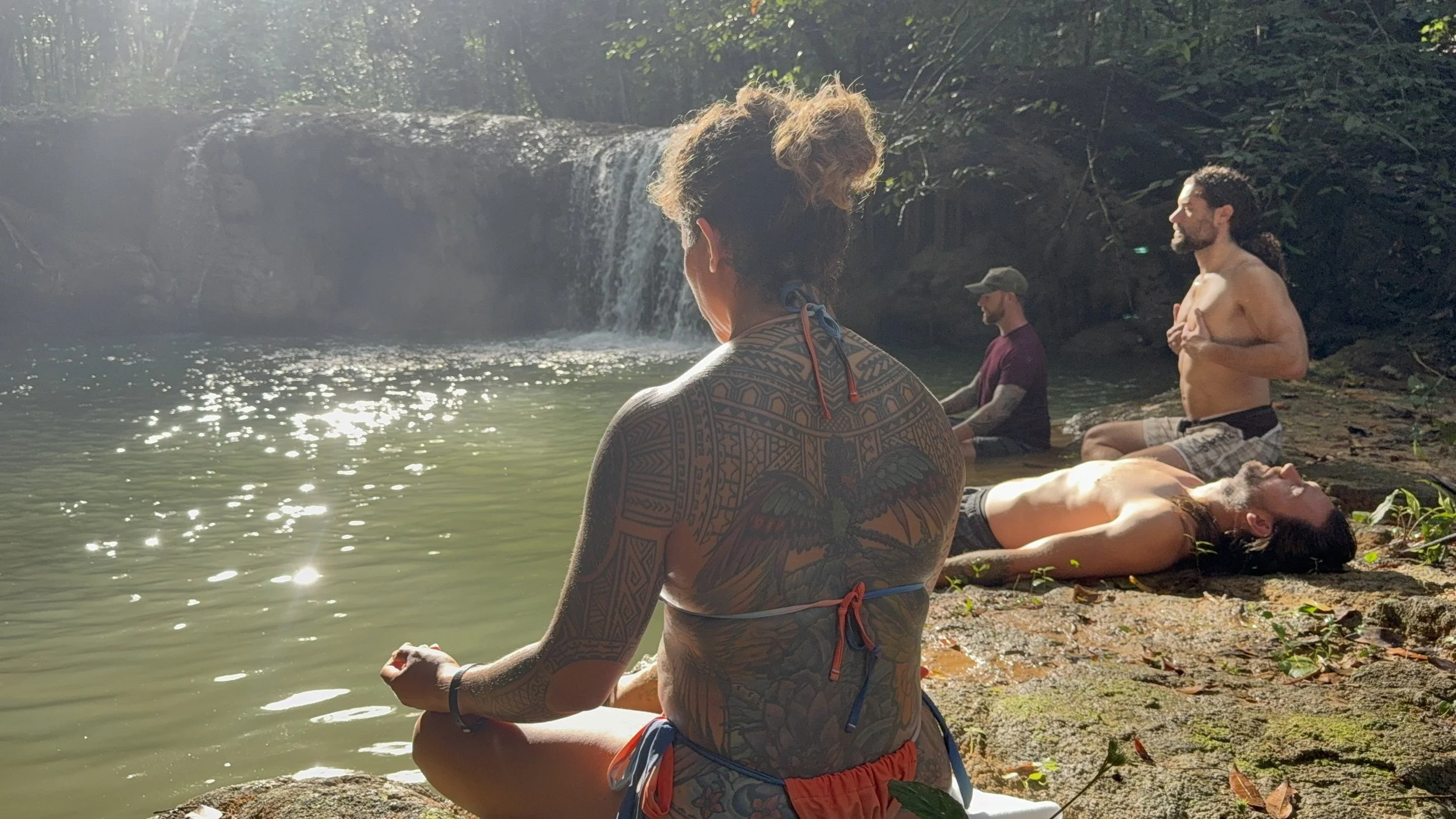 Samantha Juan participating in an outdoor meditation beside a forest waterfall