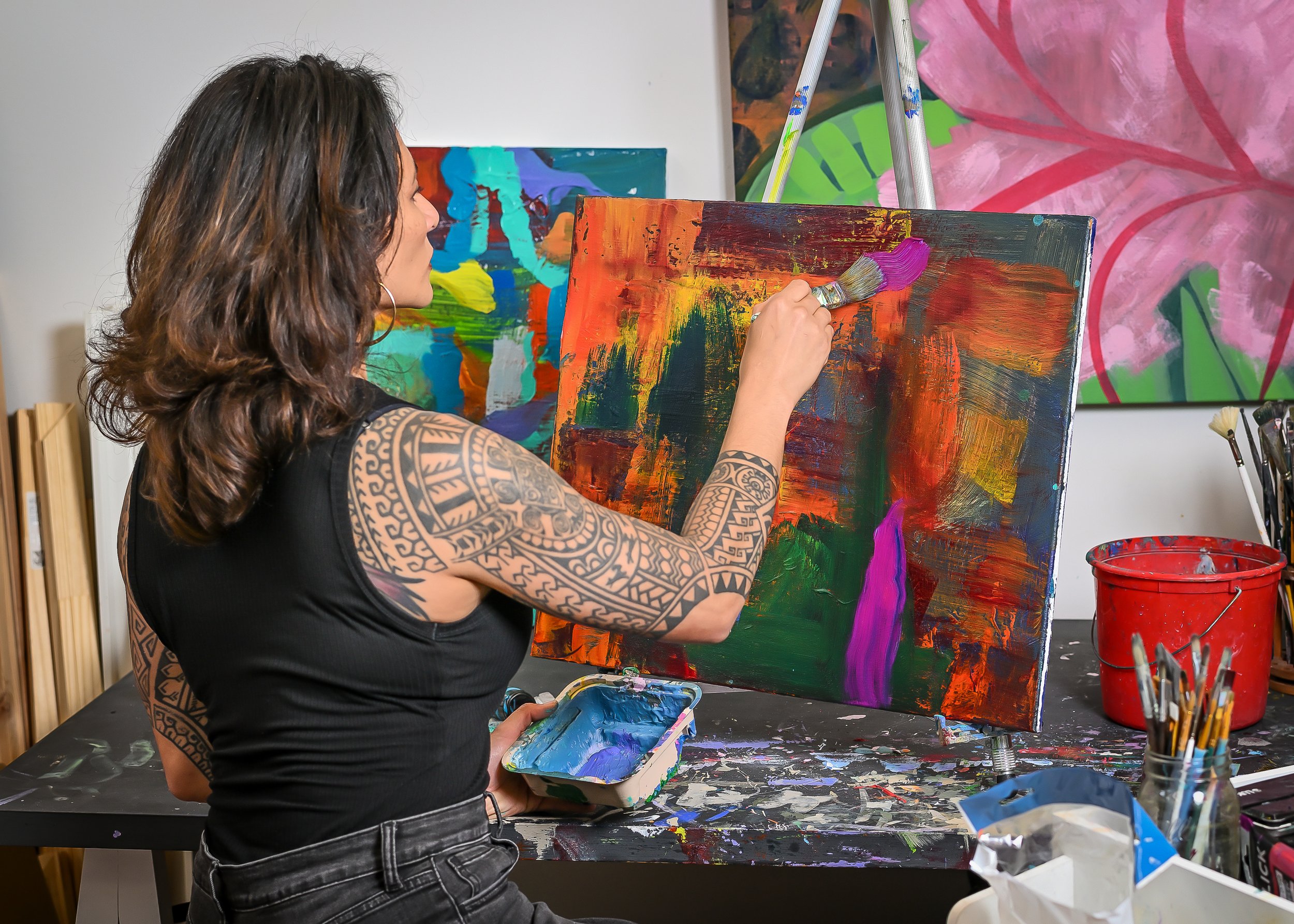 Samantha Juan painting a colorful abstract artwork in her studio.