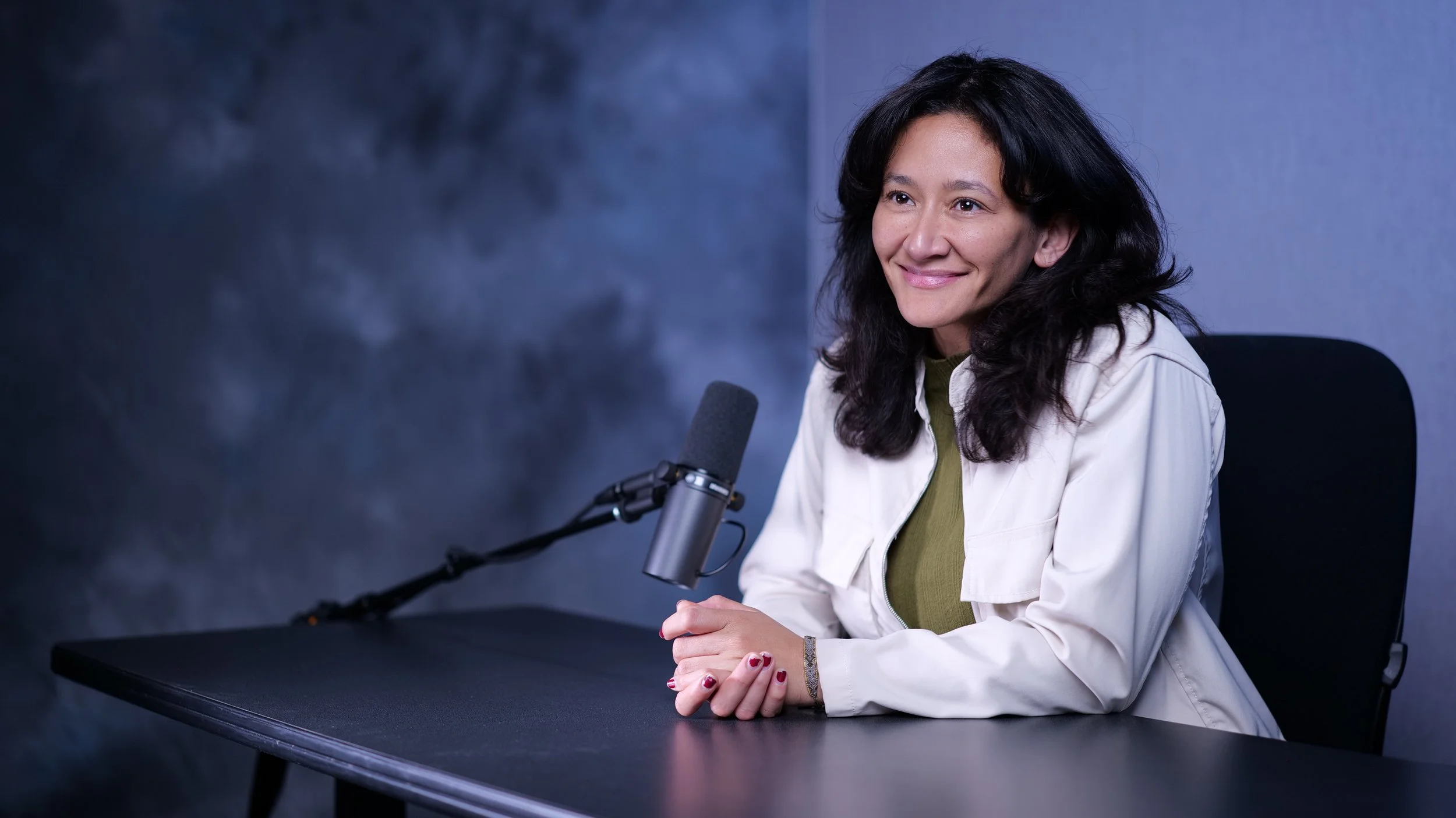 Samantha Juan smiling while speaking into a professional microphone during a podcast interview.