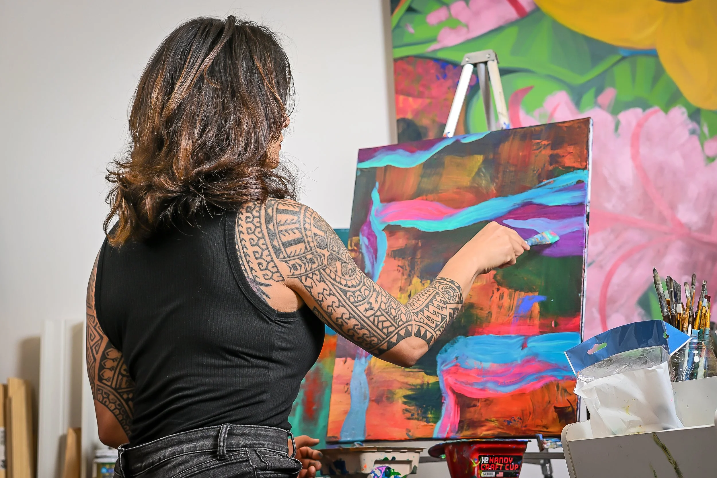 Samantha Juan painting a colorful abstract artwork in her studio.