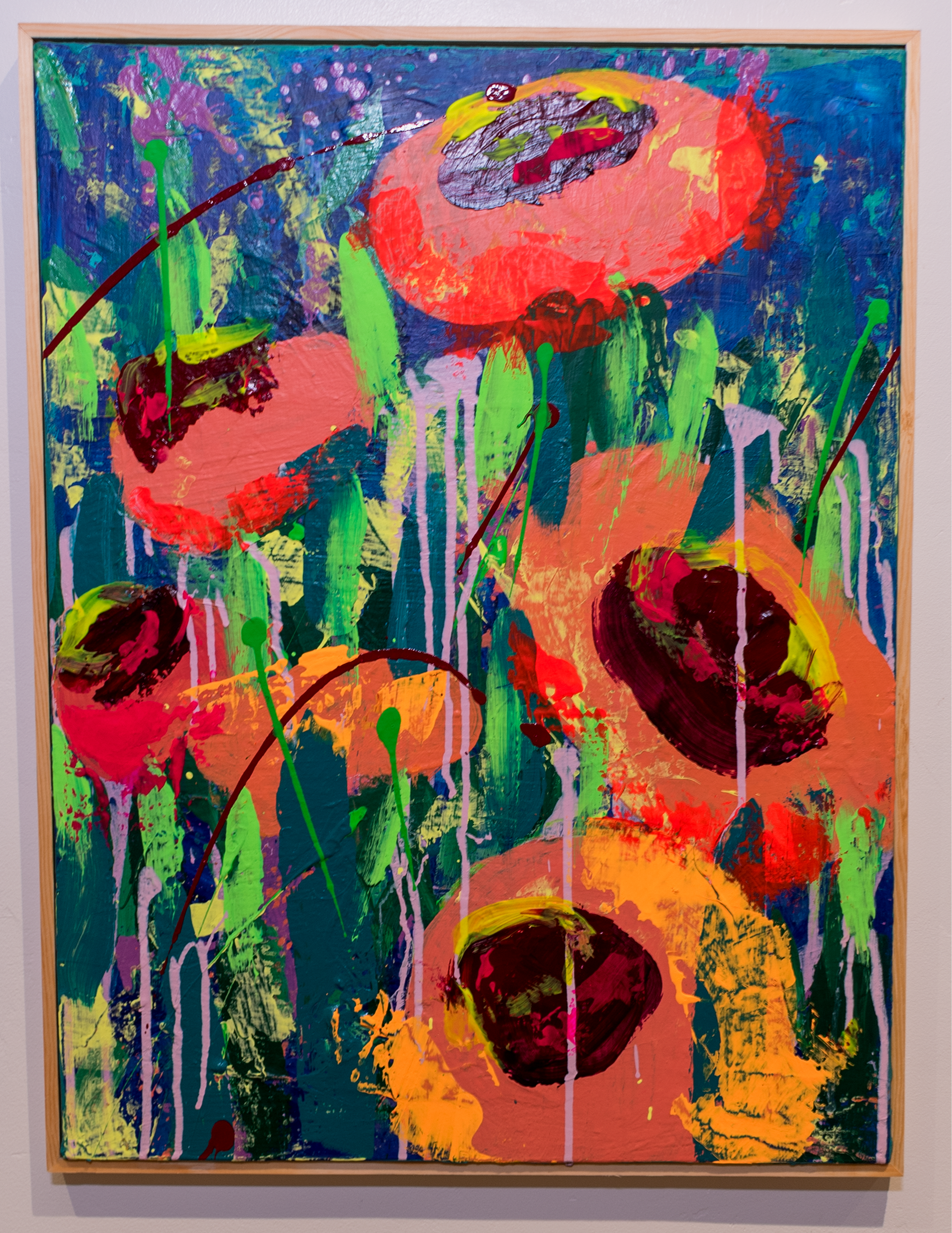 Abstract colorful painting with vibrant hues of red, green, yellow, purple, blue, and pink, featuring bold brushstrokes and drips within a wooden frame.