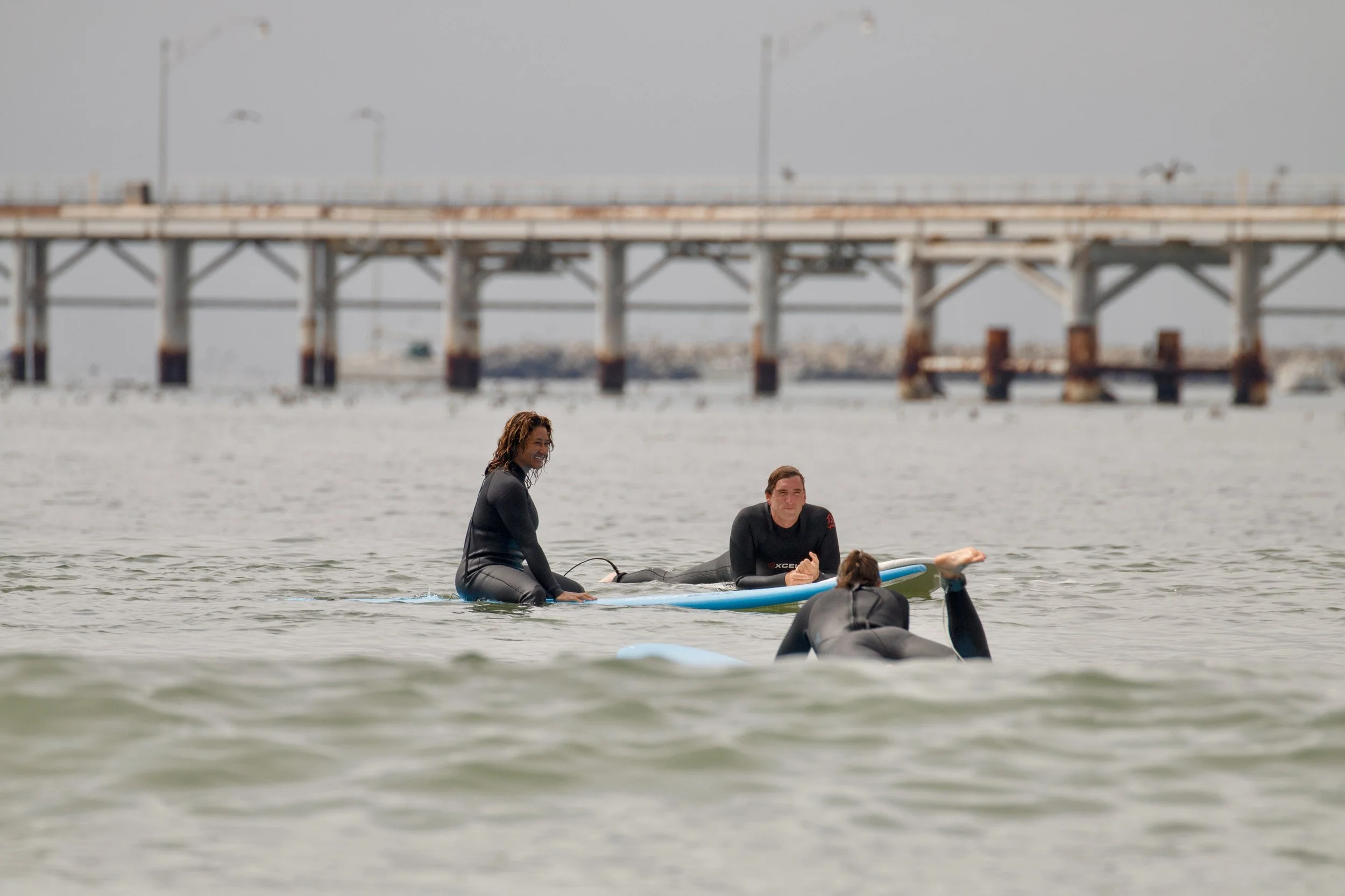 Samantha Juan and others wearing wetsuits and balancing together on a paddleboard during an MIIT activity.