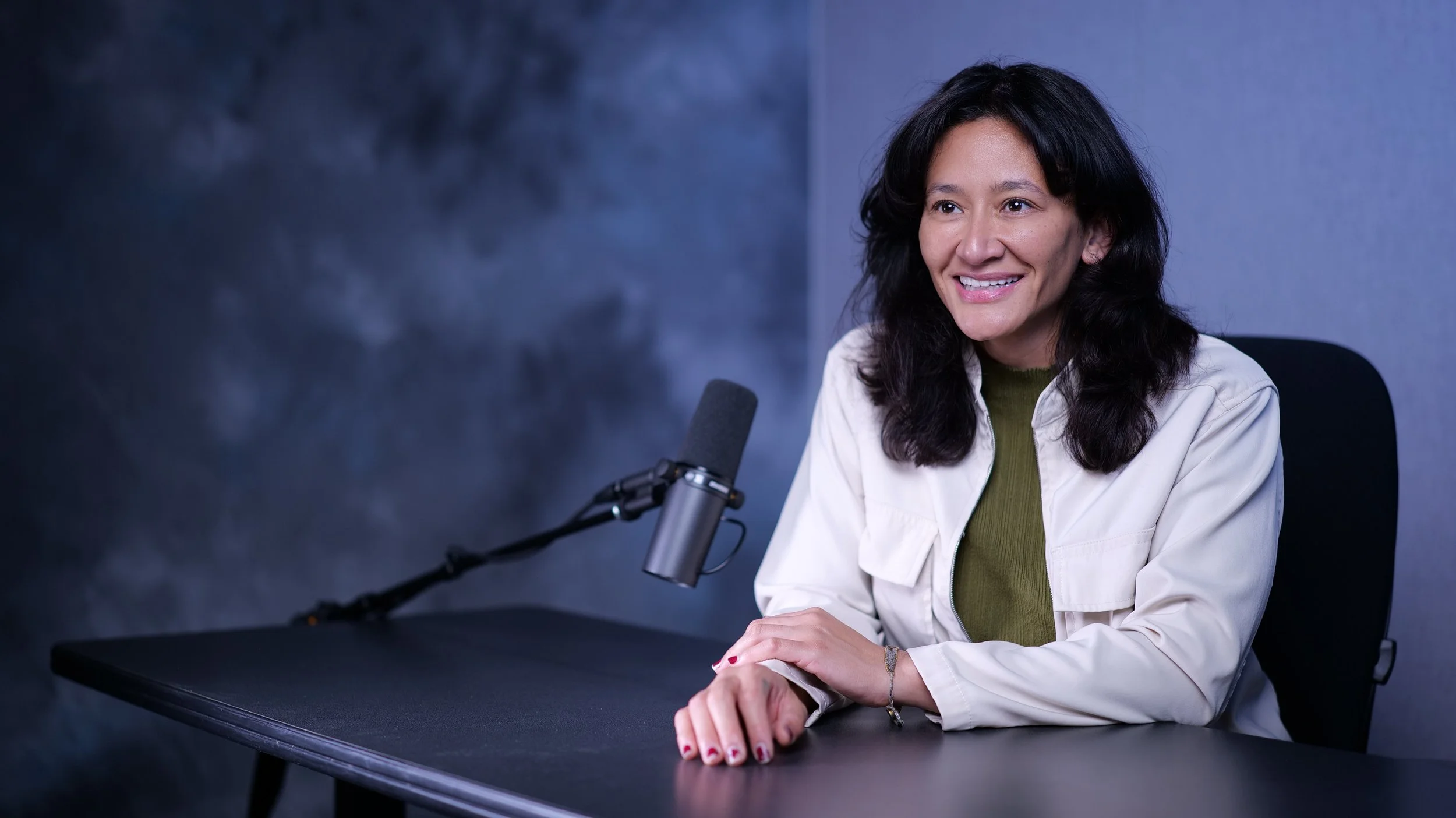 Samantha Juan smiling while speaking into a professional microphone during a podcast interview.