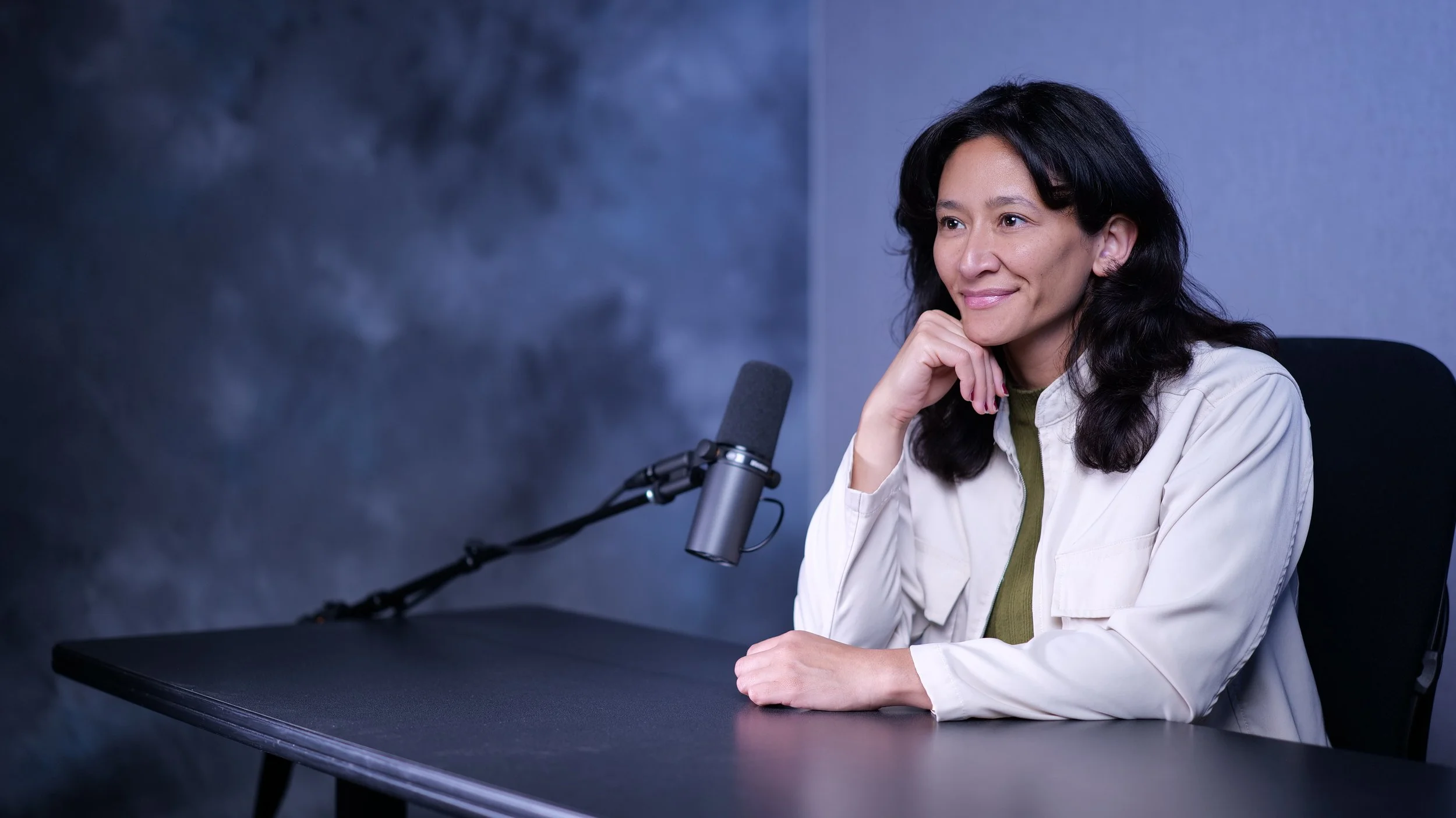 Samantha Juan smiling while speaking into a microphone during a podcast interview.