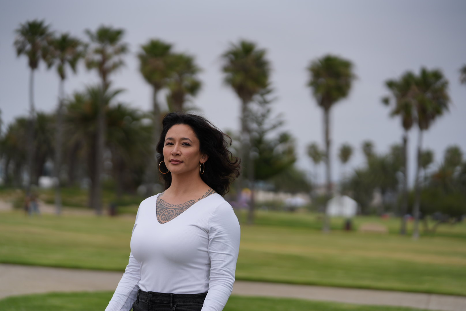 Samantha Juan standing in front of tall palm trees on a cloudy day.