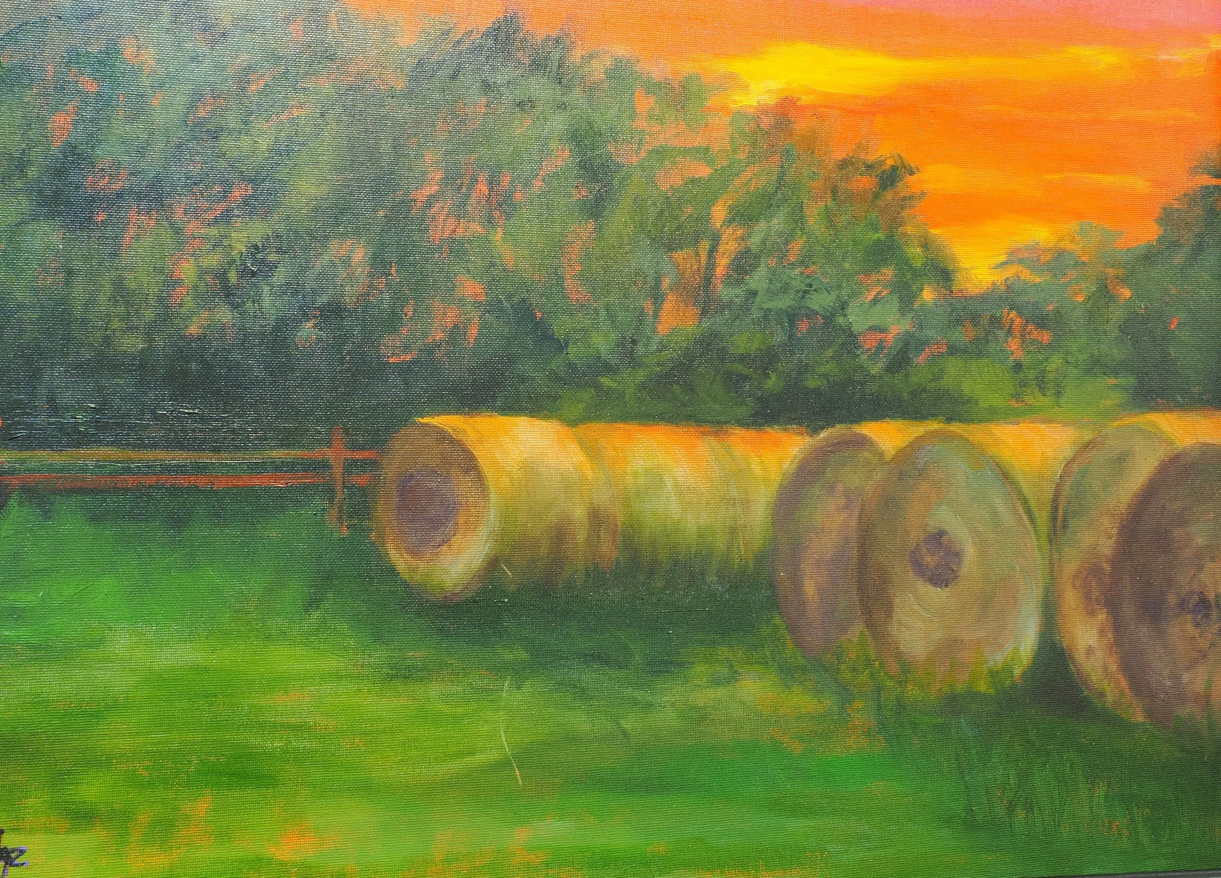 A painted landscape scene with a bright orange and yellow sky, green trees, and some hay bales on the ground.