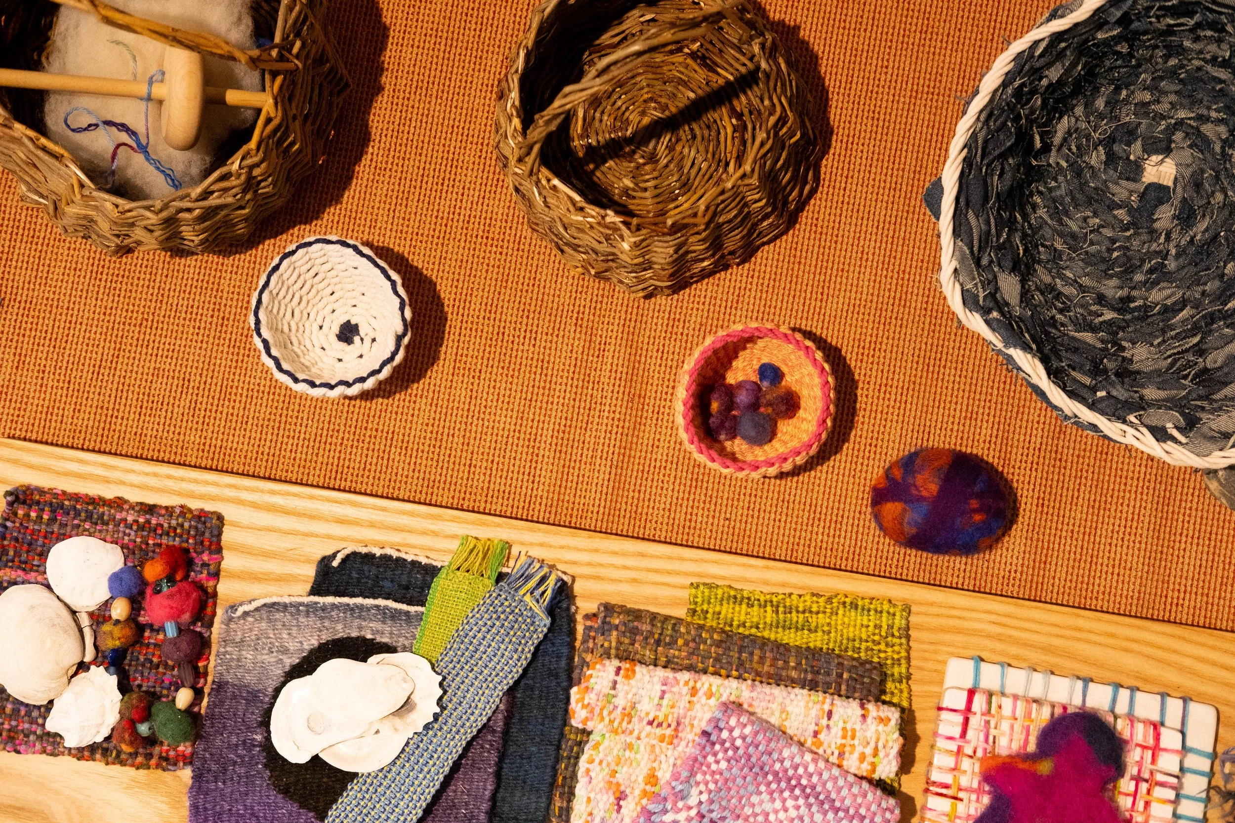 Collection of handmade craft items including baskets, woven patches, and fabric pieces displayed on an orange placemat.