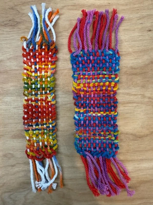 Two colorful woven friendship bracelets made from multicolored threads on a wooden surface.