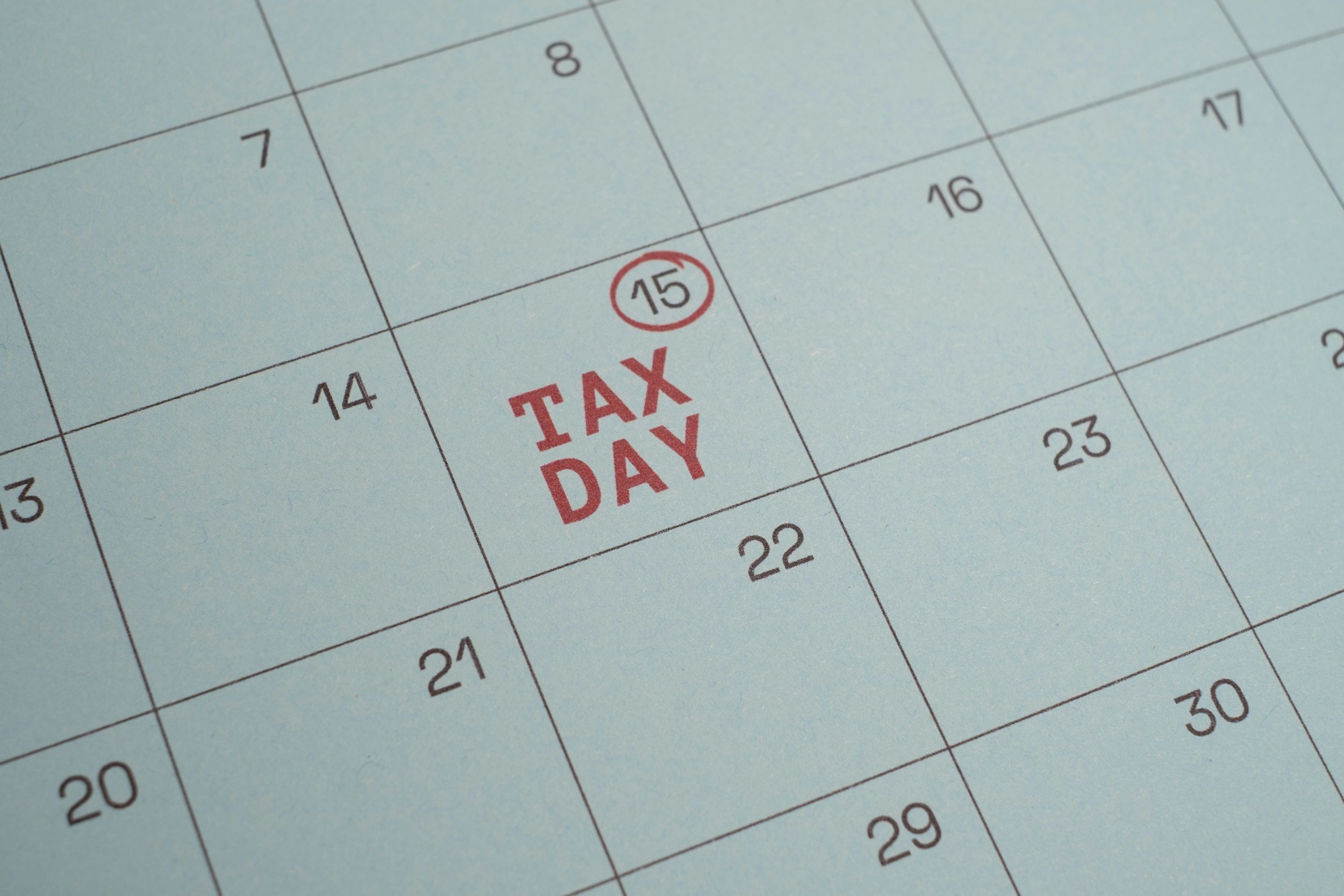 Close-up of a calendar showing the date 15 marked with a red circle and labeled 'TAX DAY' in red text.