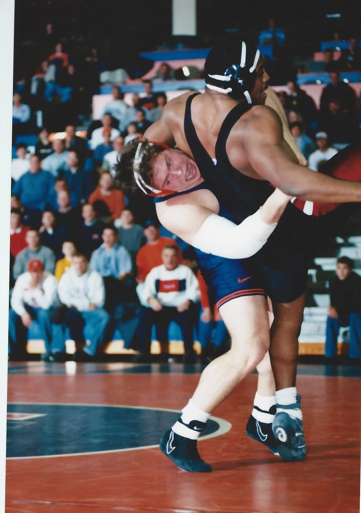 Dr. John Lockhart senior, lifting Indiana opponent to return them to the mat, competing safely with right elbow injury, stabilize with tape by his excellent athletic trainer.