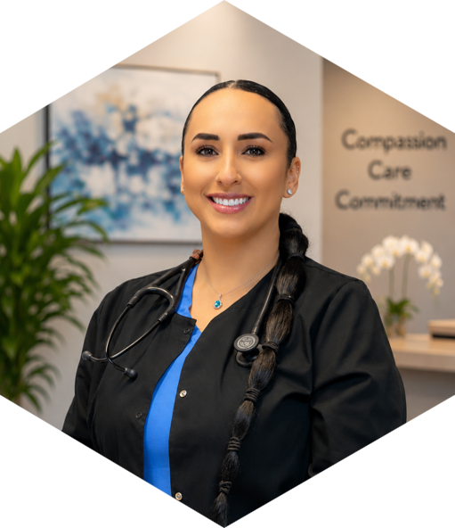 Smiling female nurse or healthcare professional with a stethoscope around her neck, wearing black scrubs in a medical office.