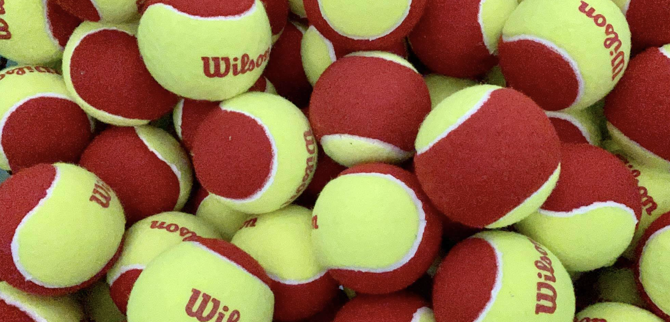 A pile of yellow and red Wilson tennis balls.