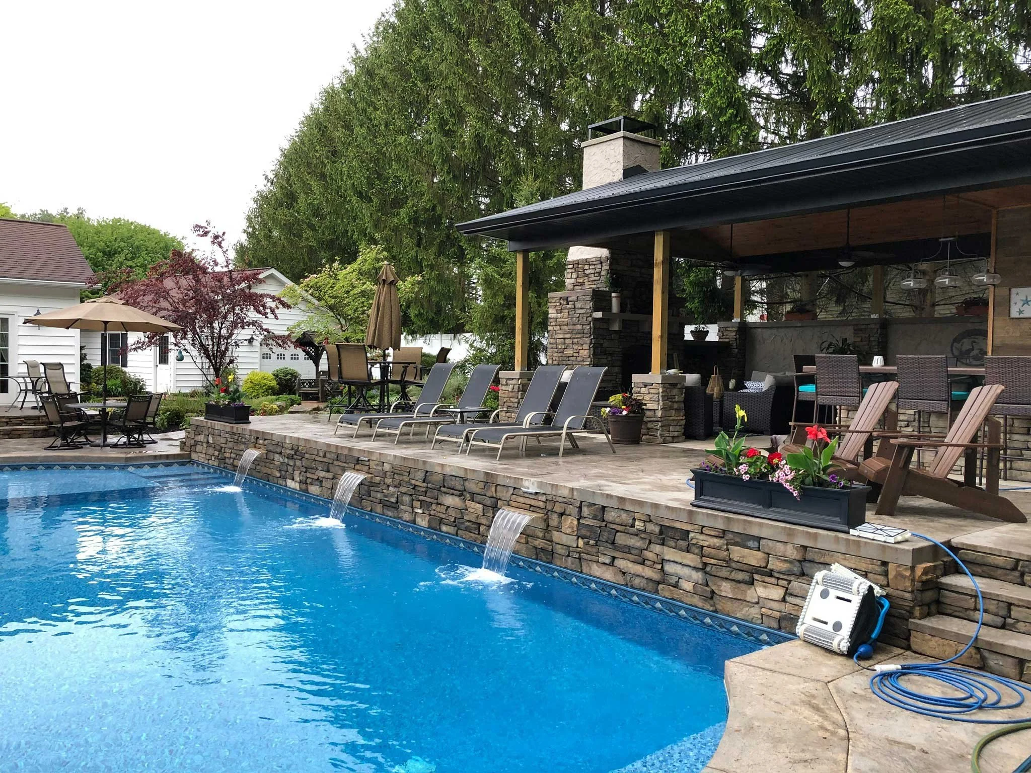 Luxury backyard pool with stone water features, covered patio, and outdoor living area