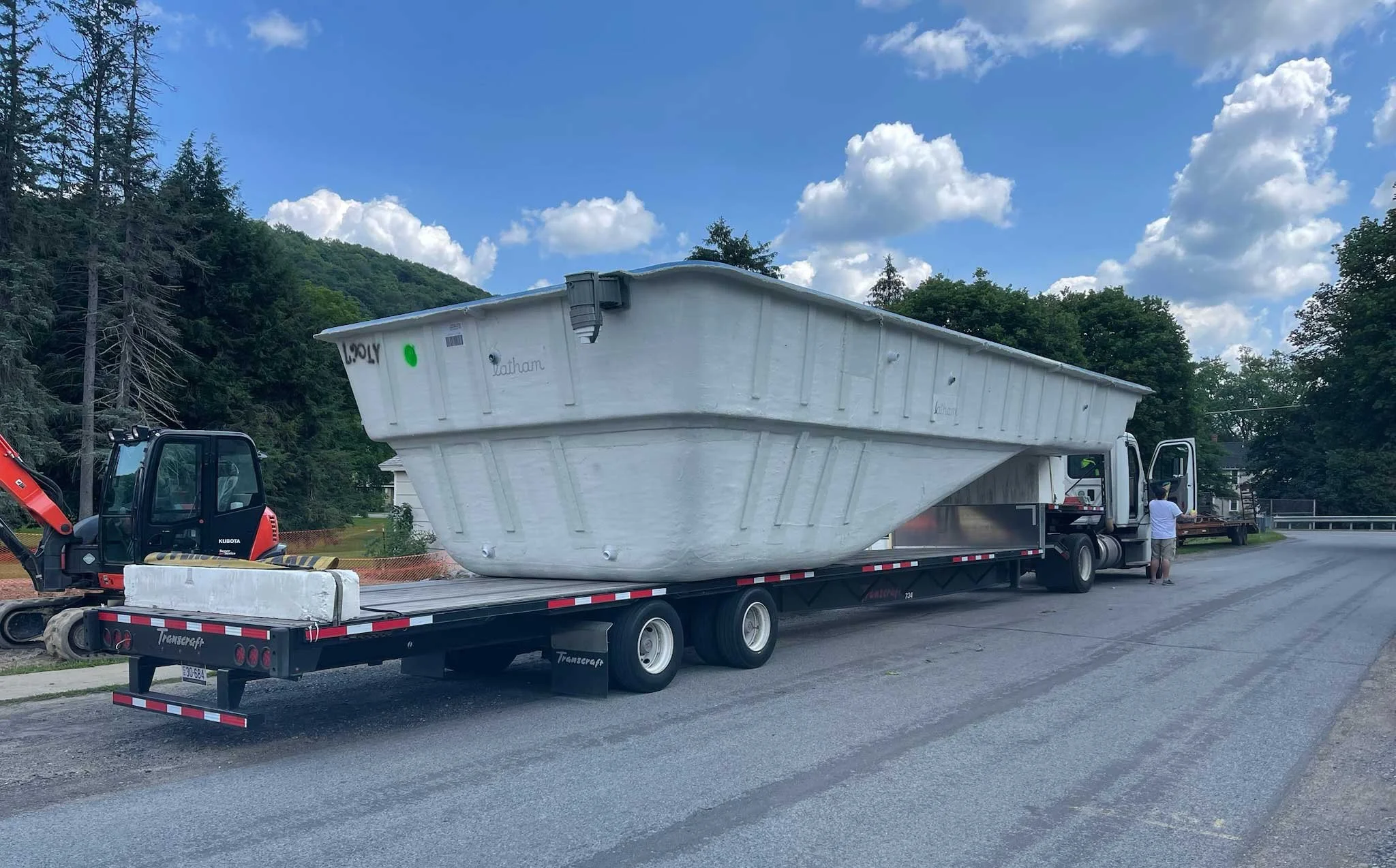Fiberglass pool shell being transported on a flatbed truck for installation

A