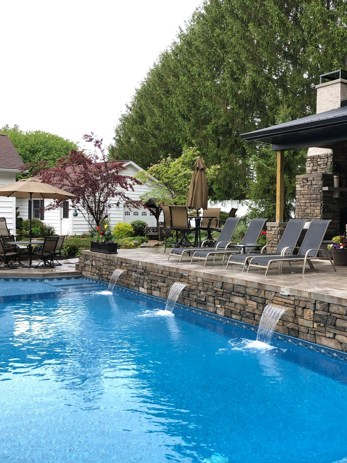 Custom backyard pool featuring water features, stone retaining walls, and outdoor living space.