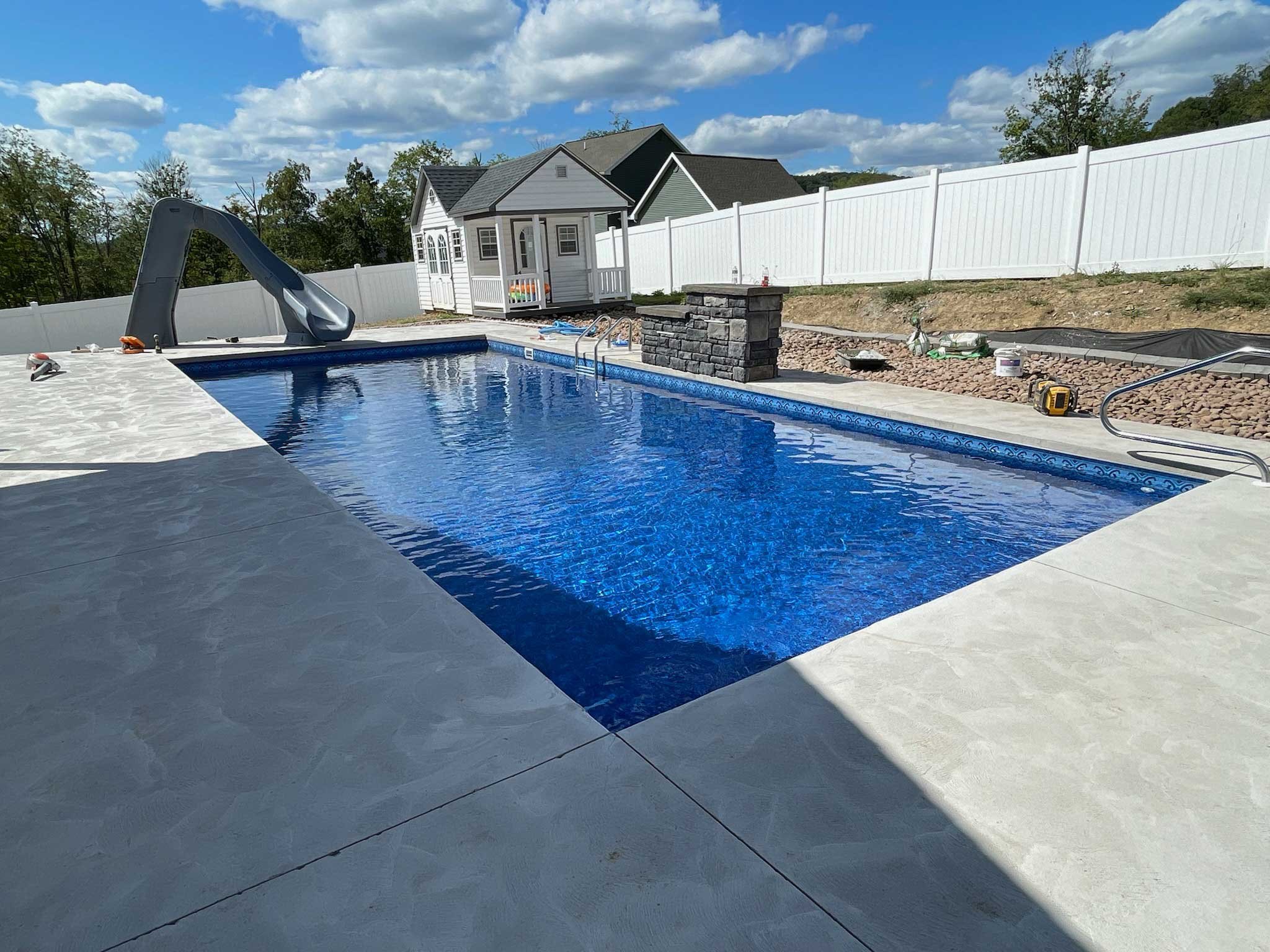 Rectangular swimming pool with slide and diving board in residential setting